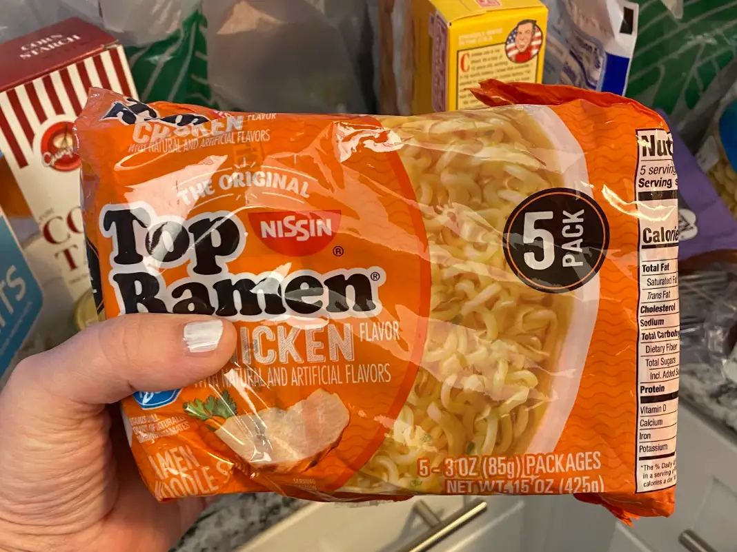 The writer holding a five-pack of Nissin Top Ramen packets.