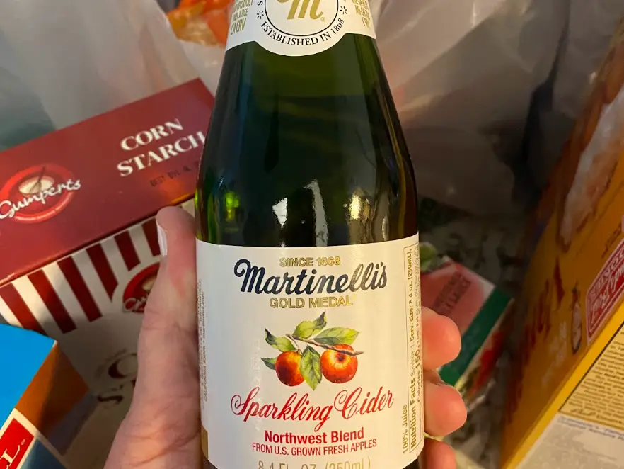 A hand holding a bottle of Martinelli's Sparkling Cider.