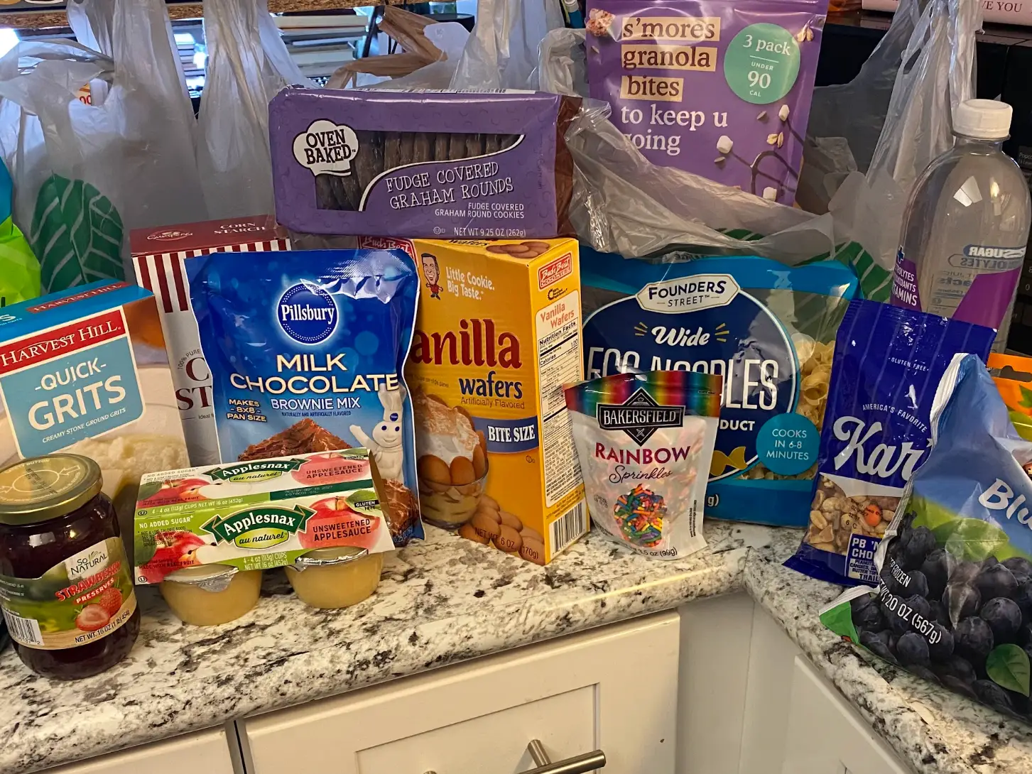 Assorted packaged groceries and pantry items from Dollar Tree are spread across a kitchen counter.