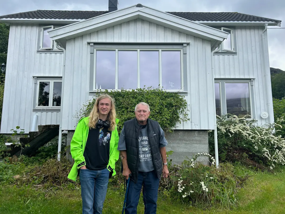Man and his grandson standing in front of home