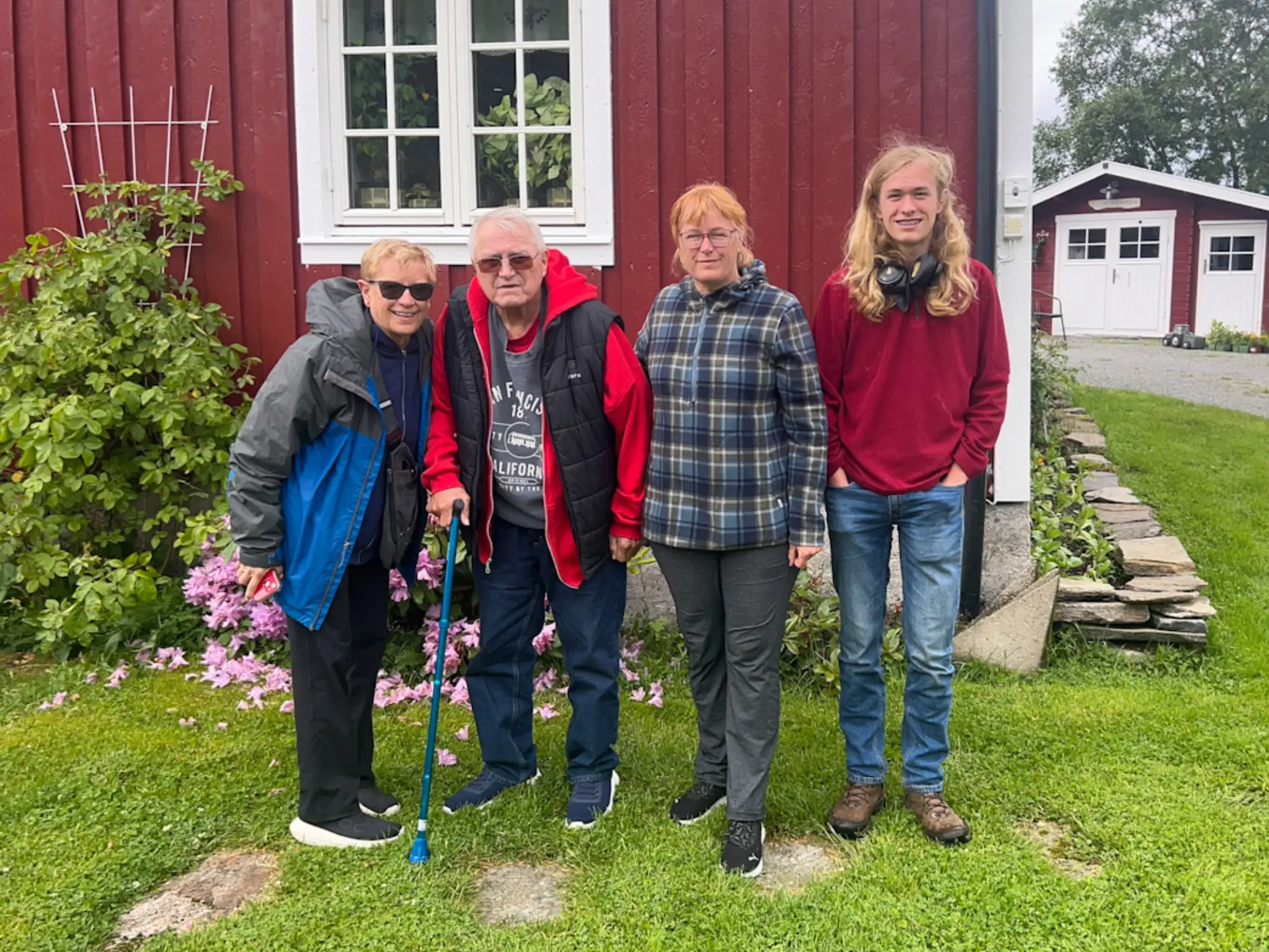 Woman smiling with son and parents in front of house on farm