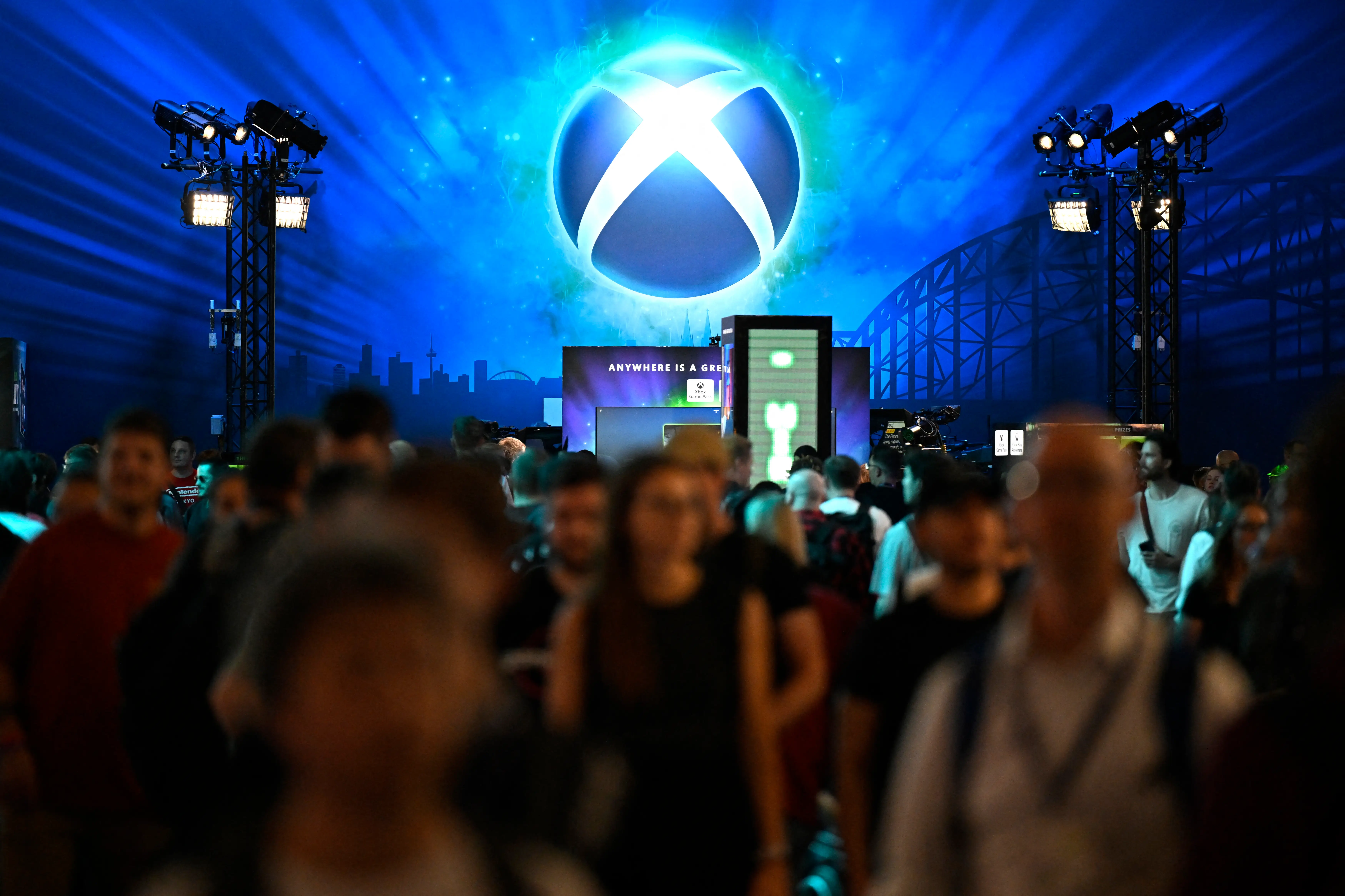 Visitors walk in front of the Xbox booth during the Gamescom video games trade fair at the Trade Fair Center in Cologne, western Germany, on the first day of the fair on August 20, 2025.