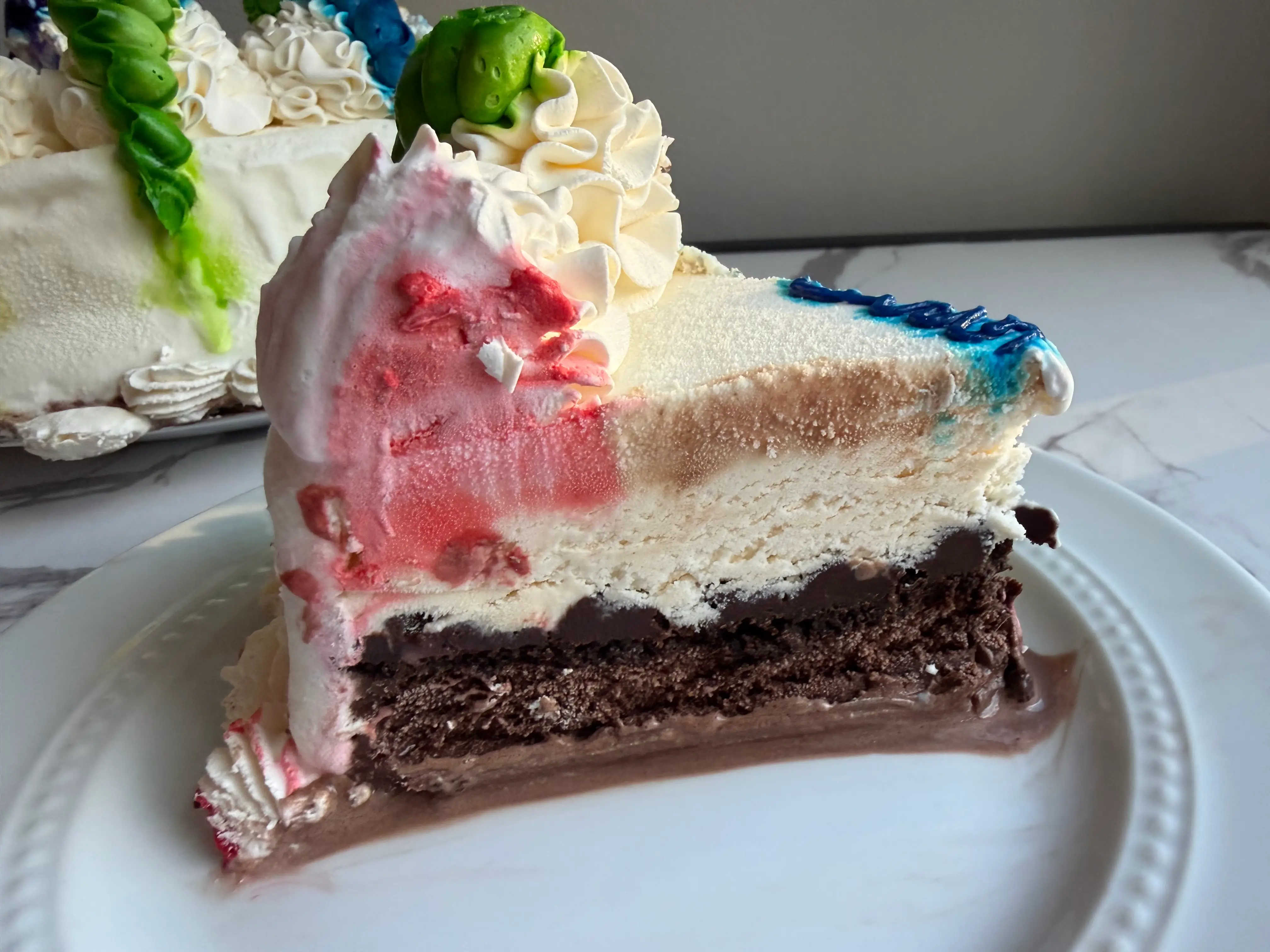 Slice of Baskin-Robbins ice cream cake with chocolate, fudge crunch, and vanilla layers