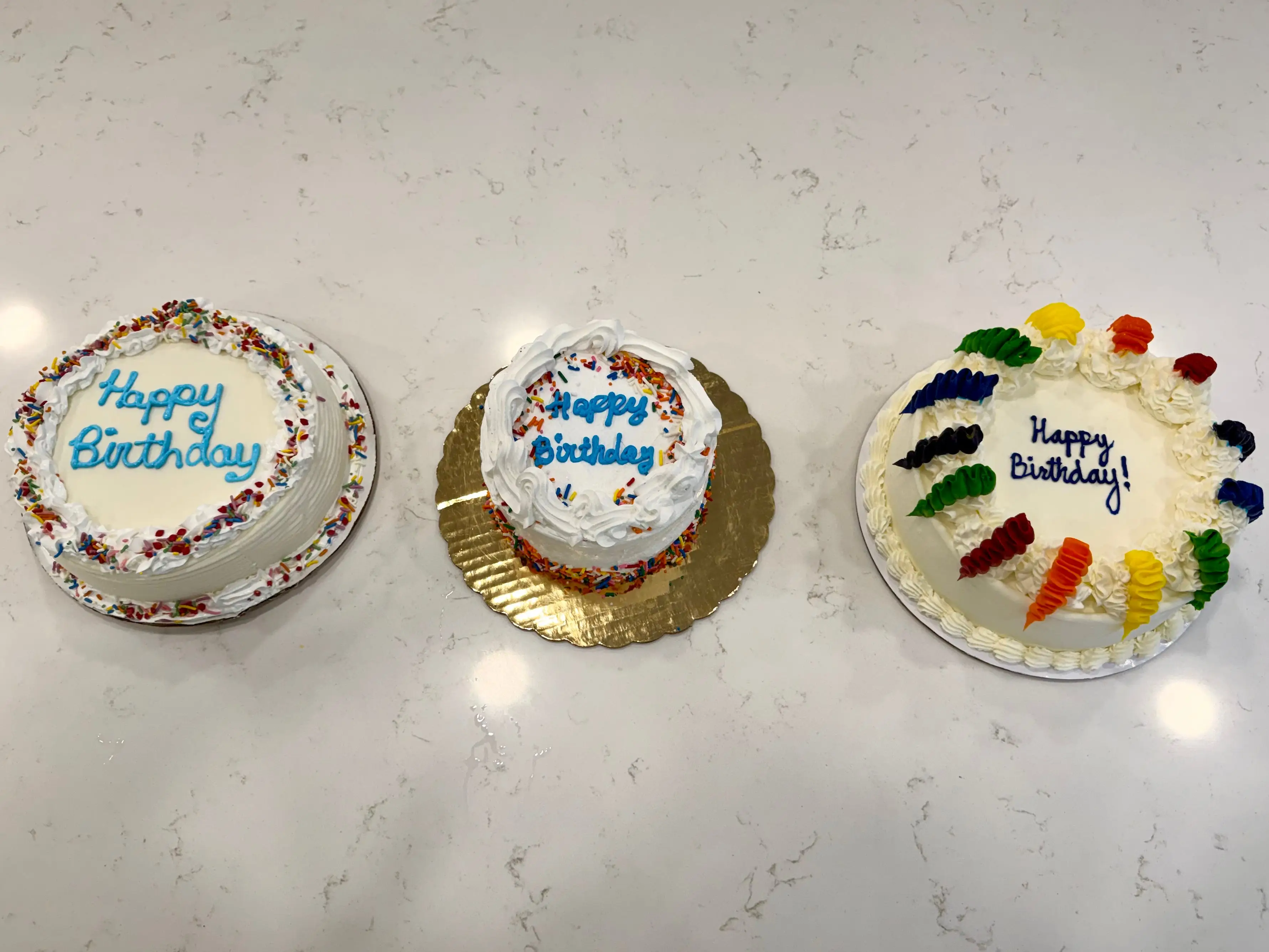 White ice cream cakes from Dairy Queen, Cold Stone Creamery, and Baskin Robbins on marble counter