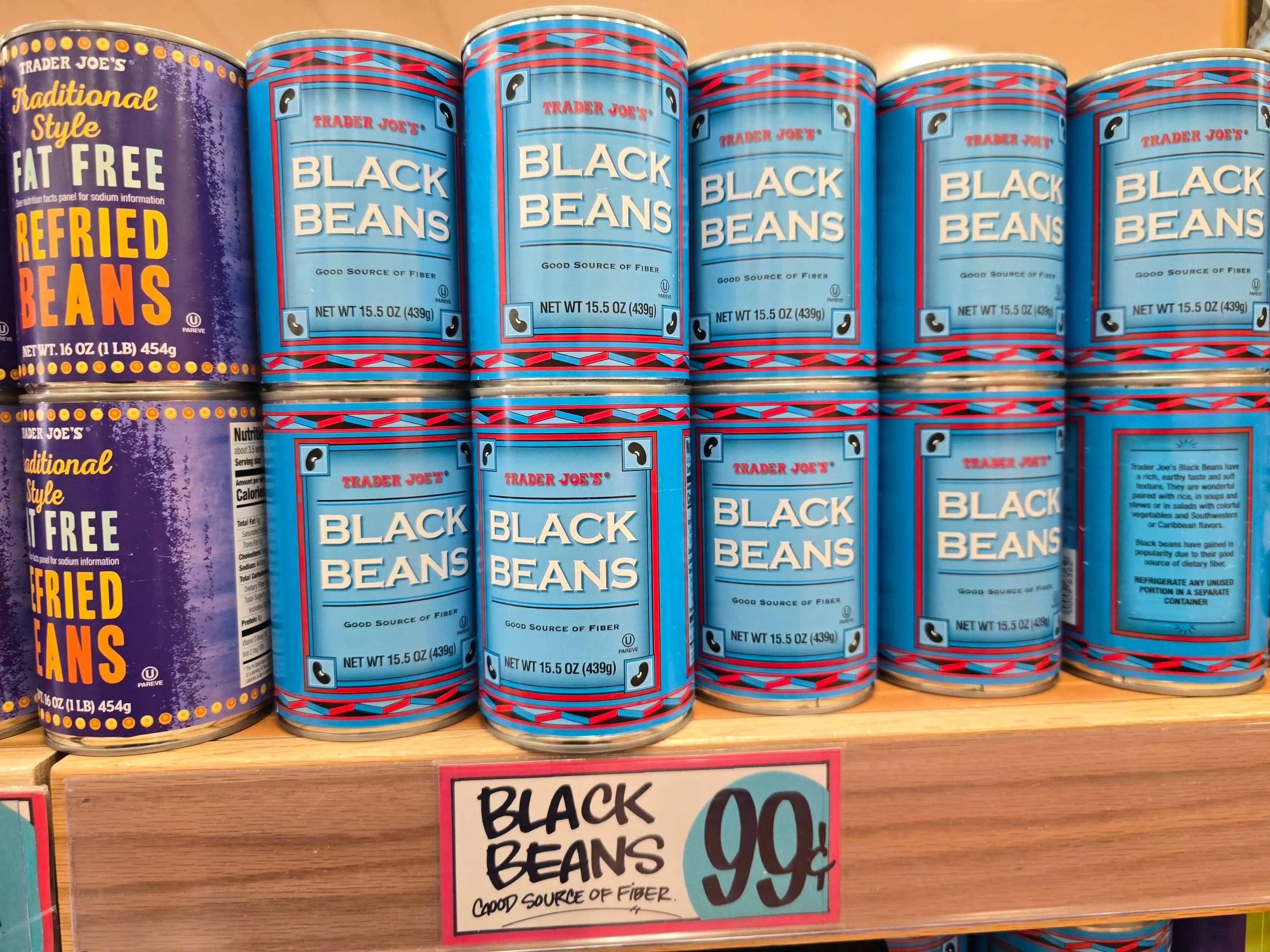 Cans of black and refried beans on a shelf at Trader Joe's.