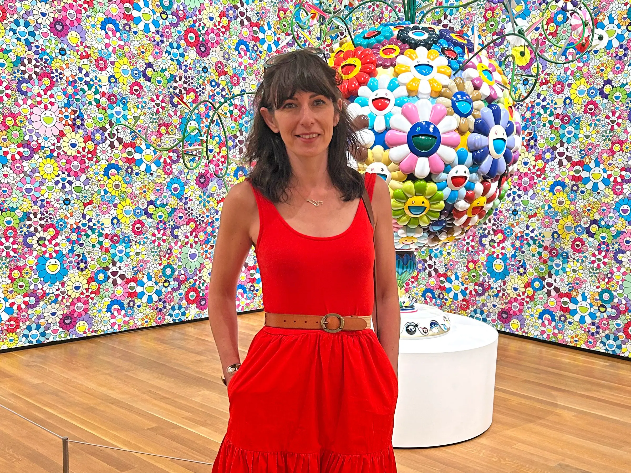 Yelena poses in front of a floral art exhibit.