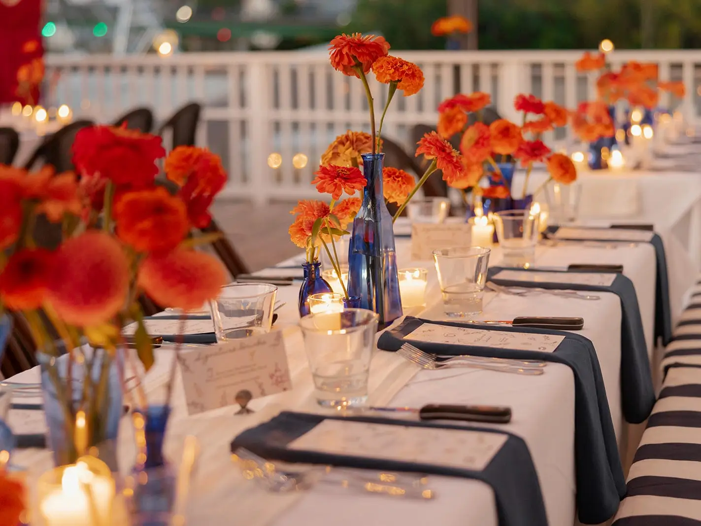 A table with blue vases and orange flowers.