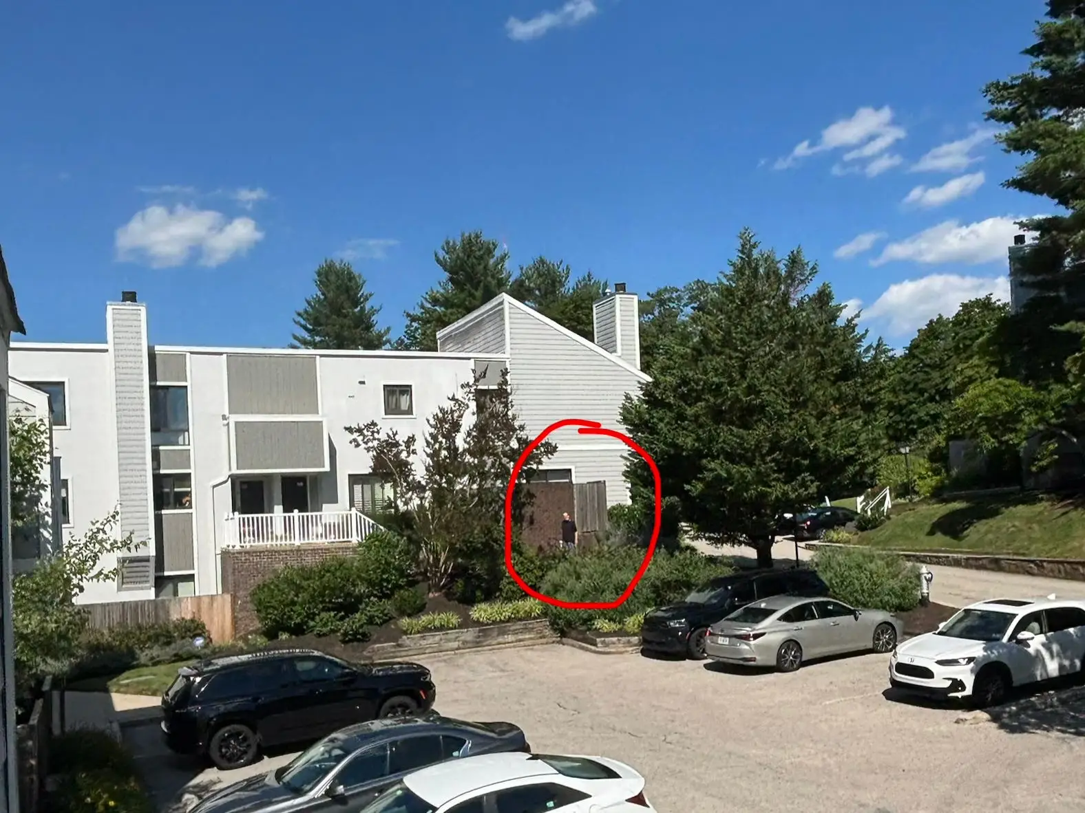 A townhouse and cars in a parking lot, with a red circle outlining a man walking by