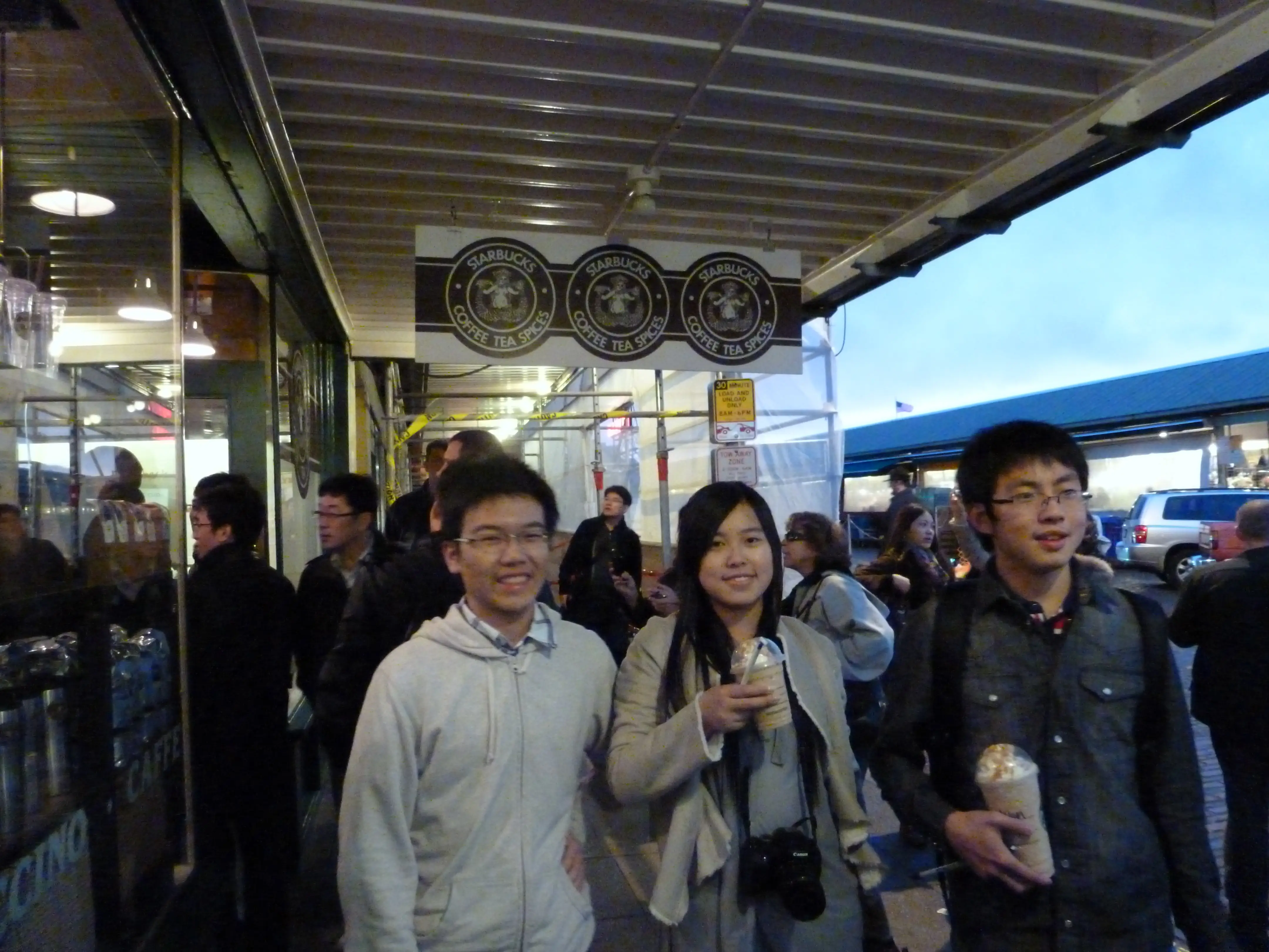 Three people walking down the street with coffees.