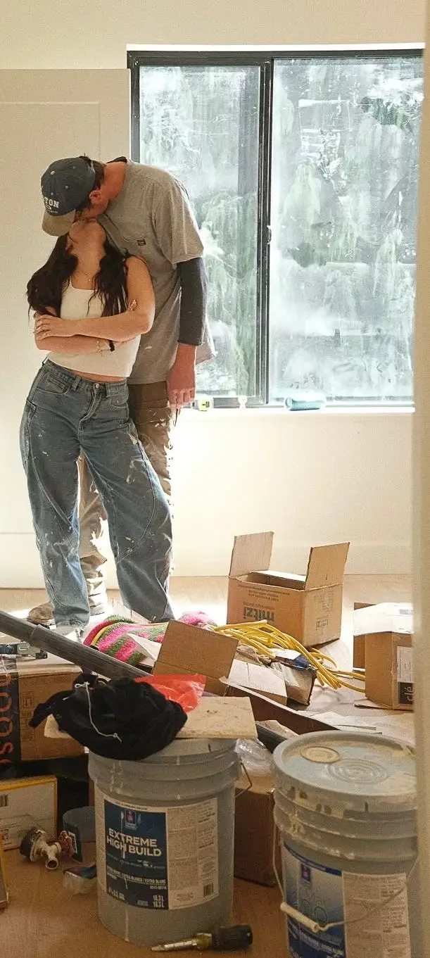 A couple kisses in a room filled with construction equipment.