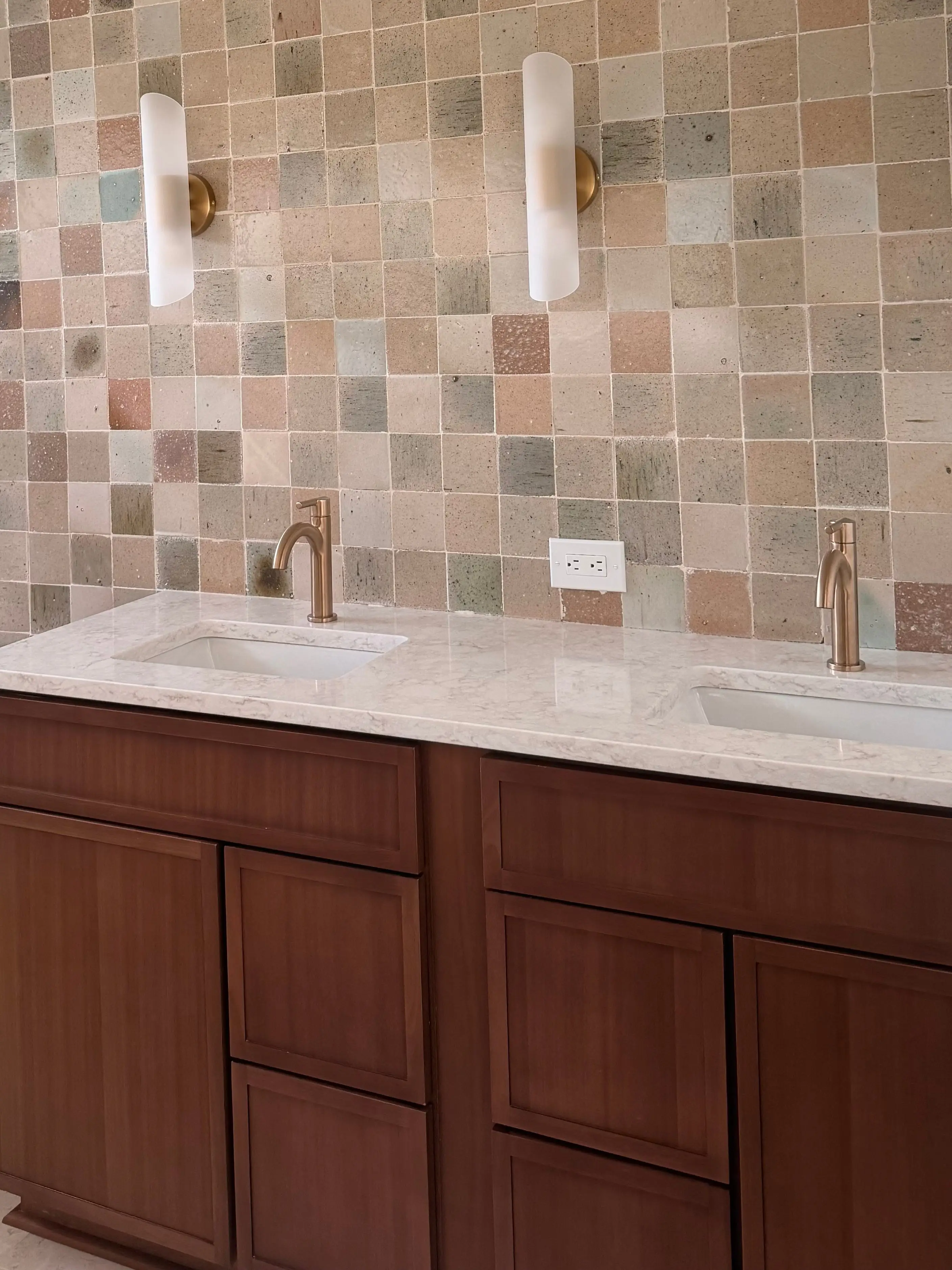 A kitchen with a multicolored tile backsplash covering the wall.