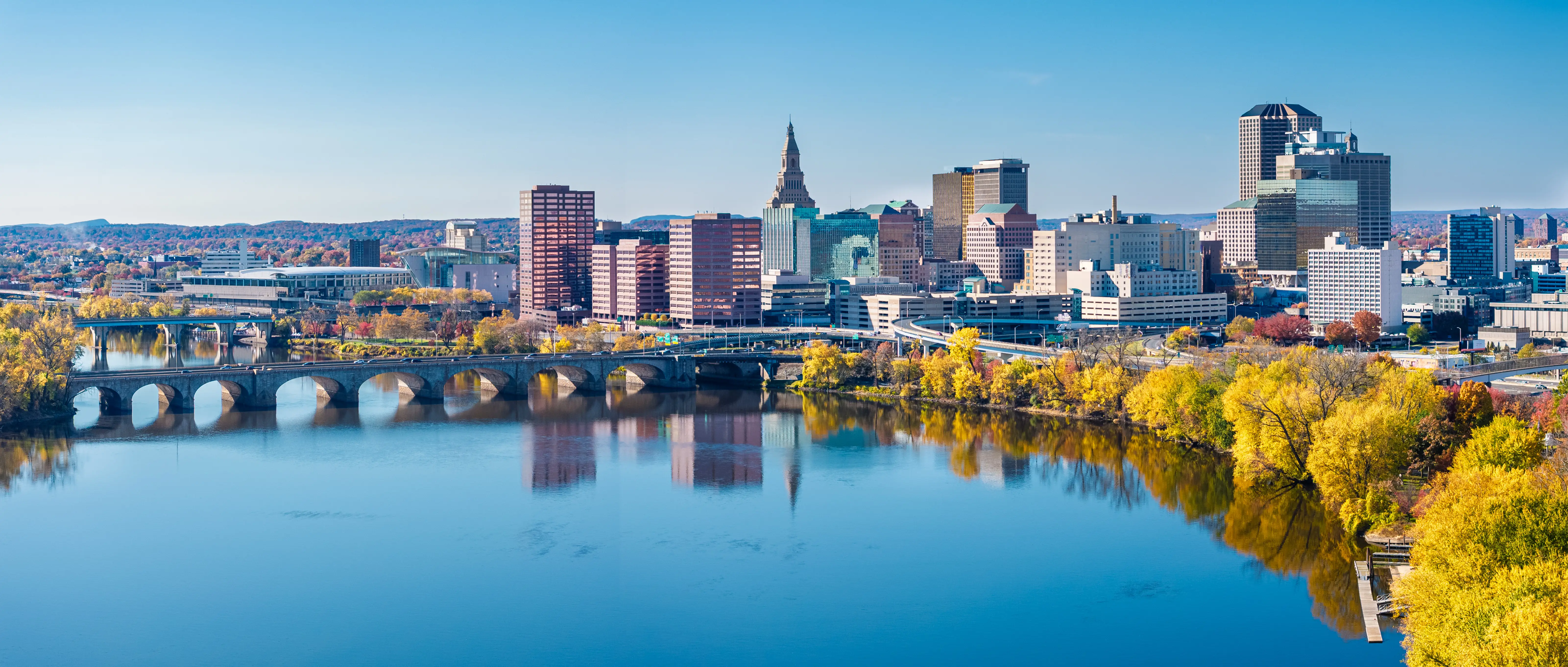 Aerial view of Hartford, Connecticut, skyline with bridge, river, and park.