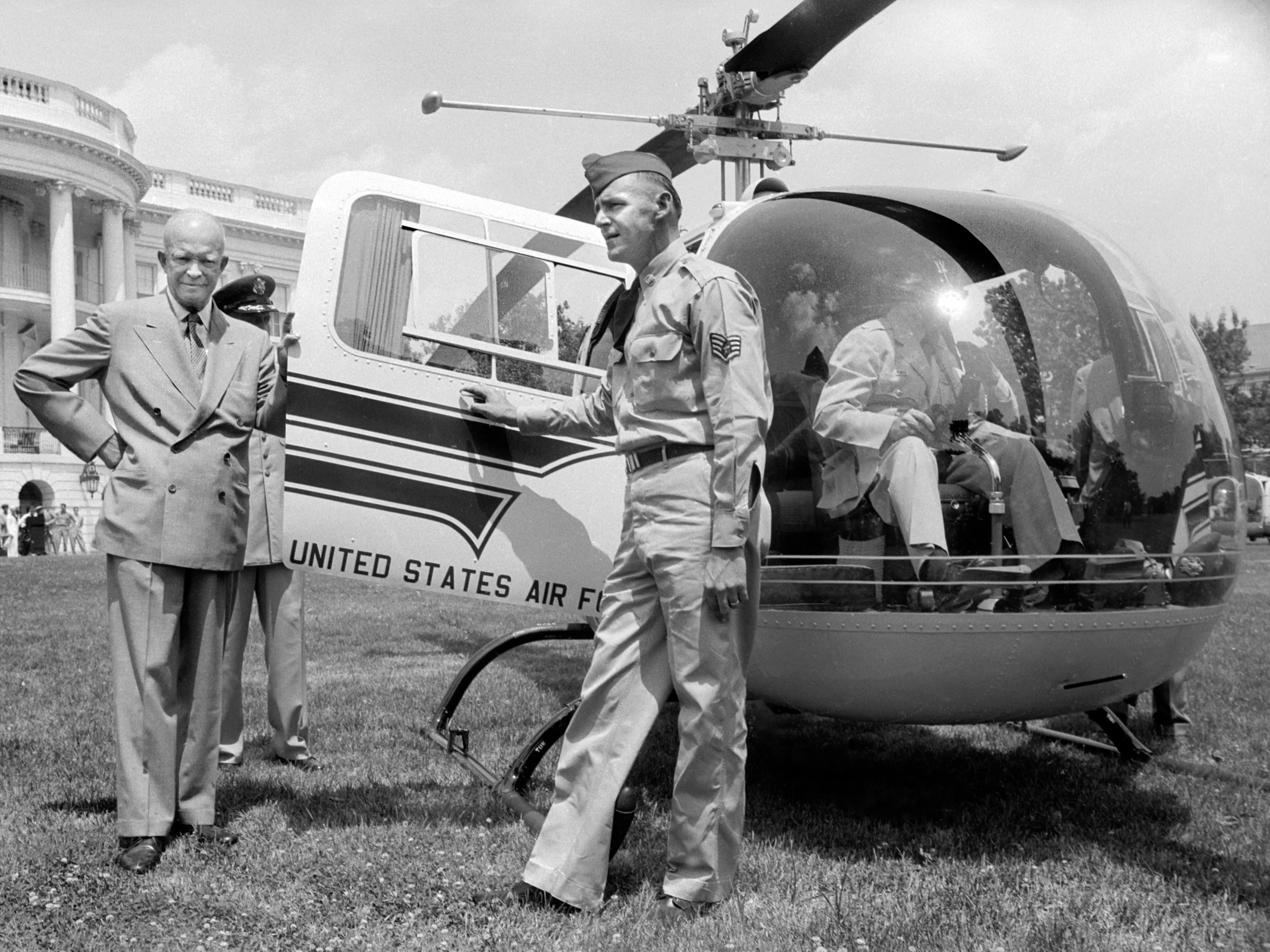 President Dwight D. Eisenhower stands next to a helicopter
