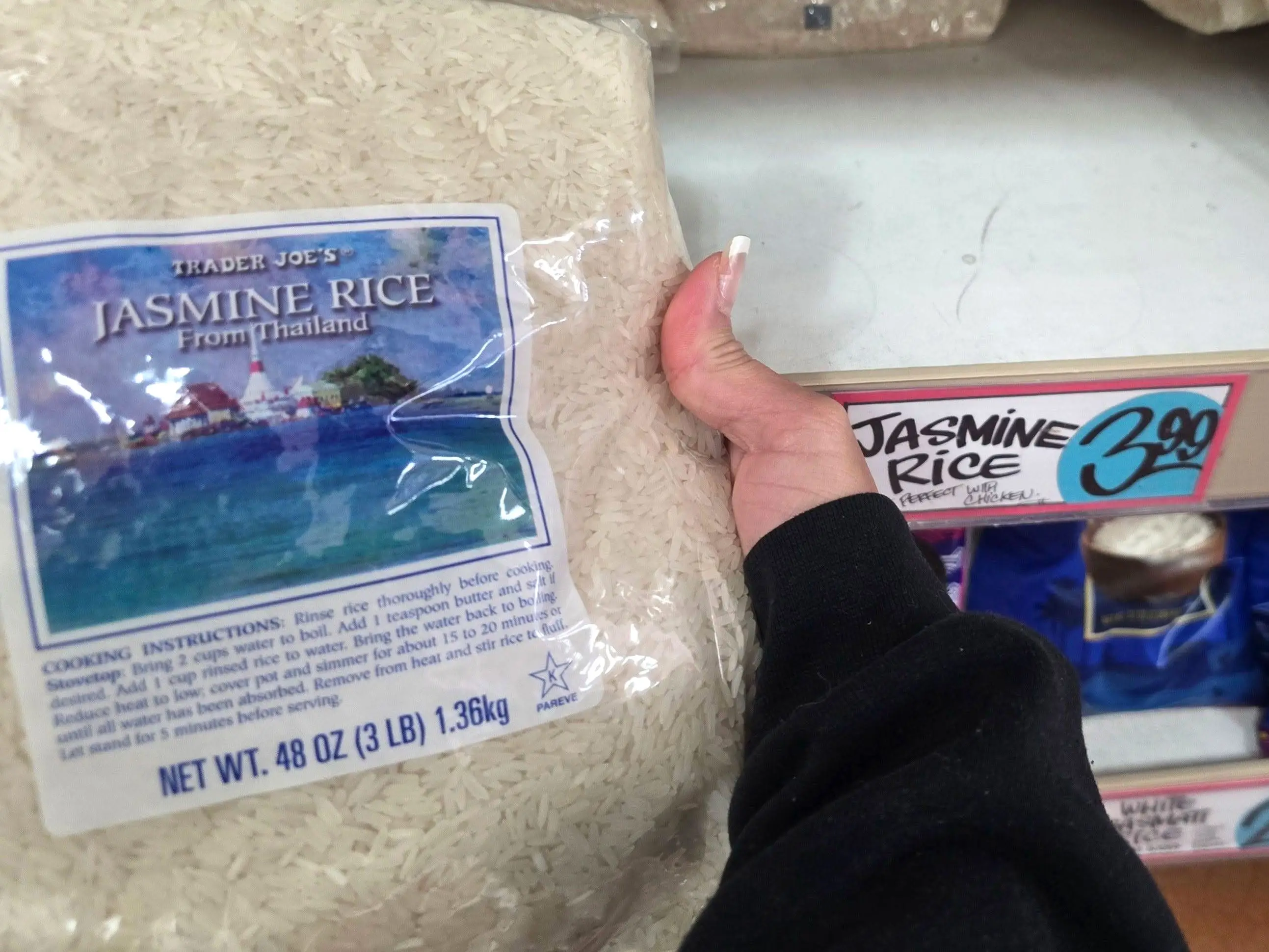 A hand holding a bag of Trader Joe's jasmine rice.