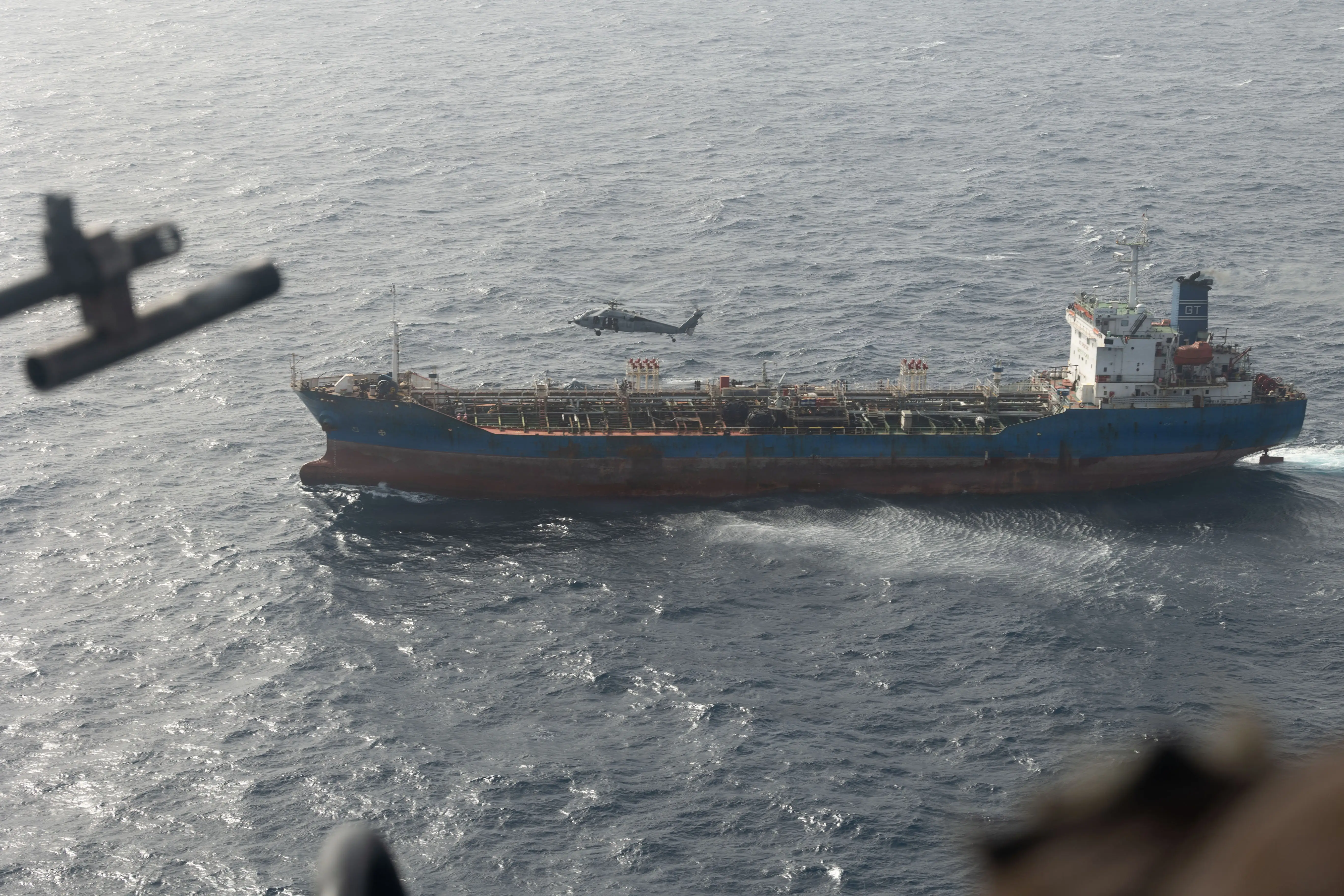 A large Iranian-flagged cargo vessel sails in blue water.