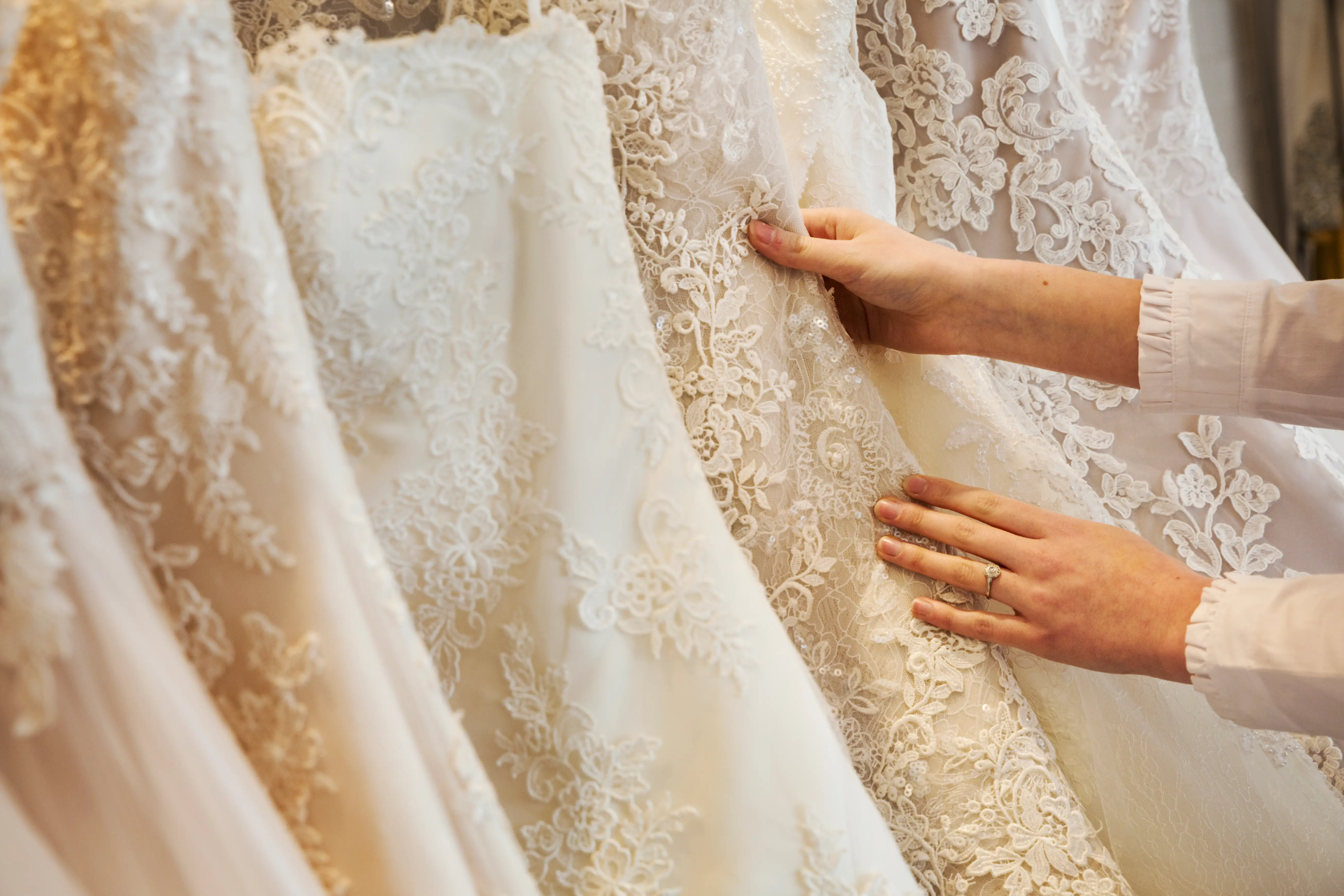 A woman looking through a rack of wedding gowns.