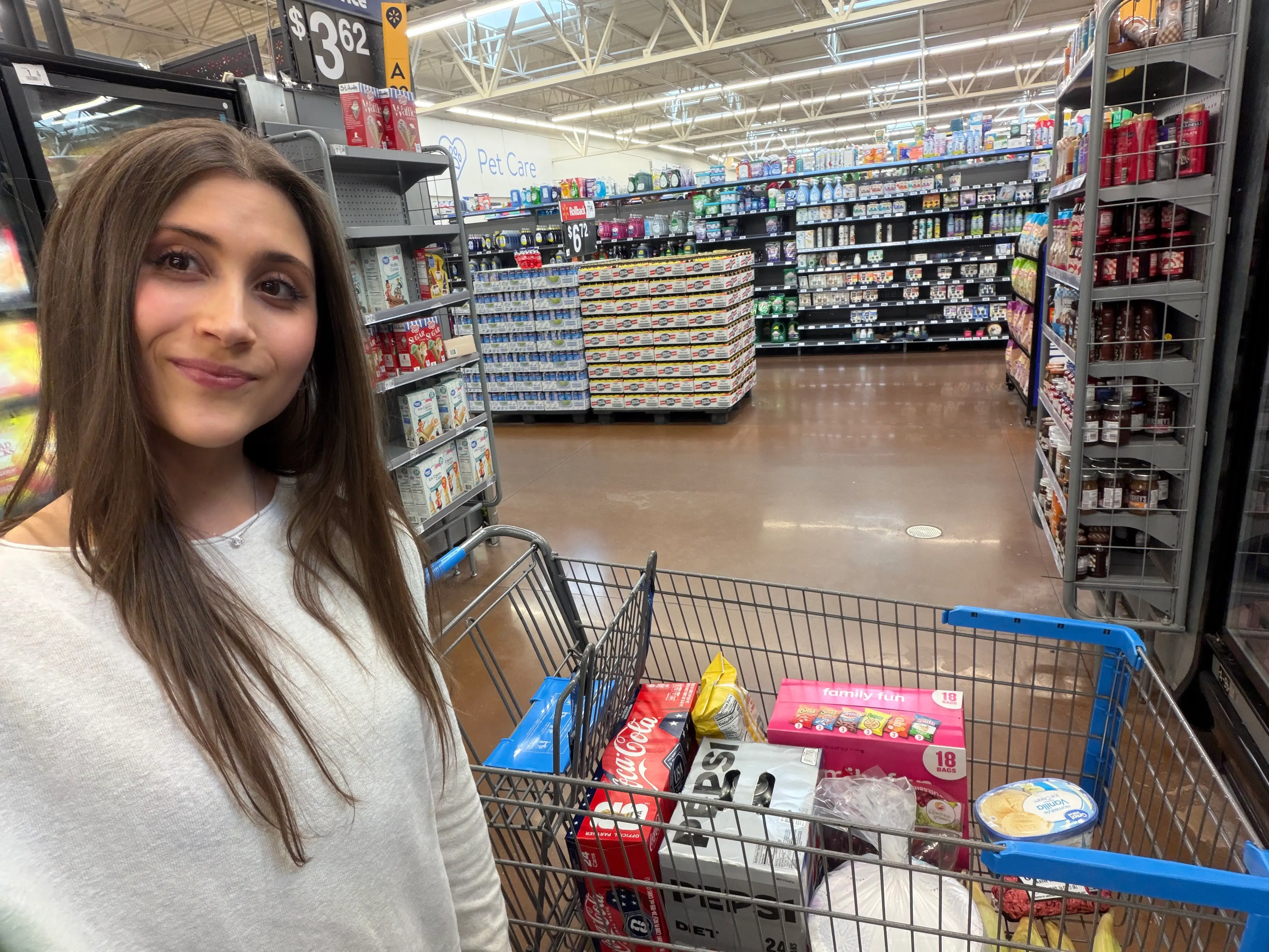 Woman smilin with cart in Walmart aisle