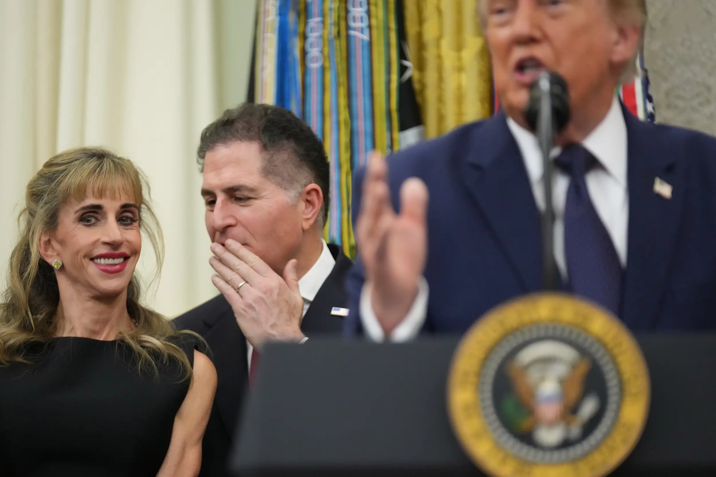 Michael Dell whispers to Susan Dell as Donald Trump speaks