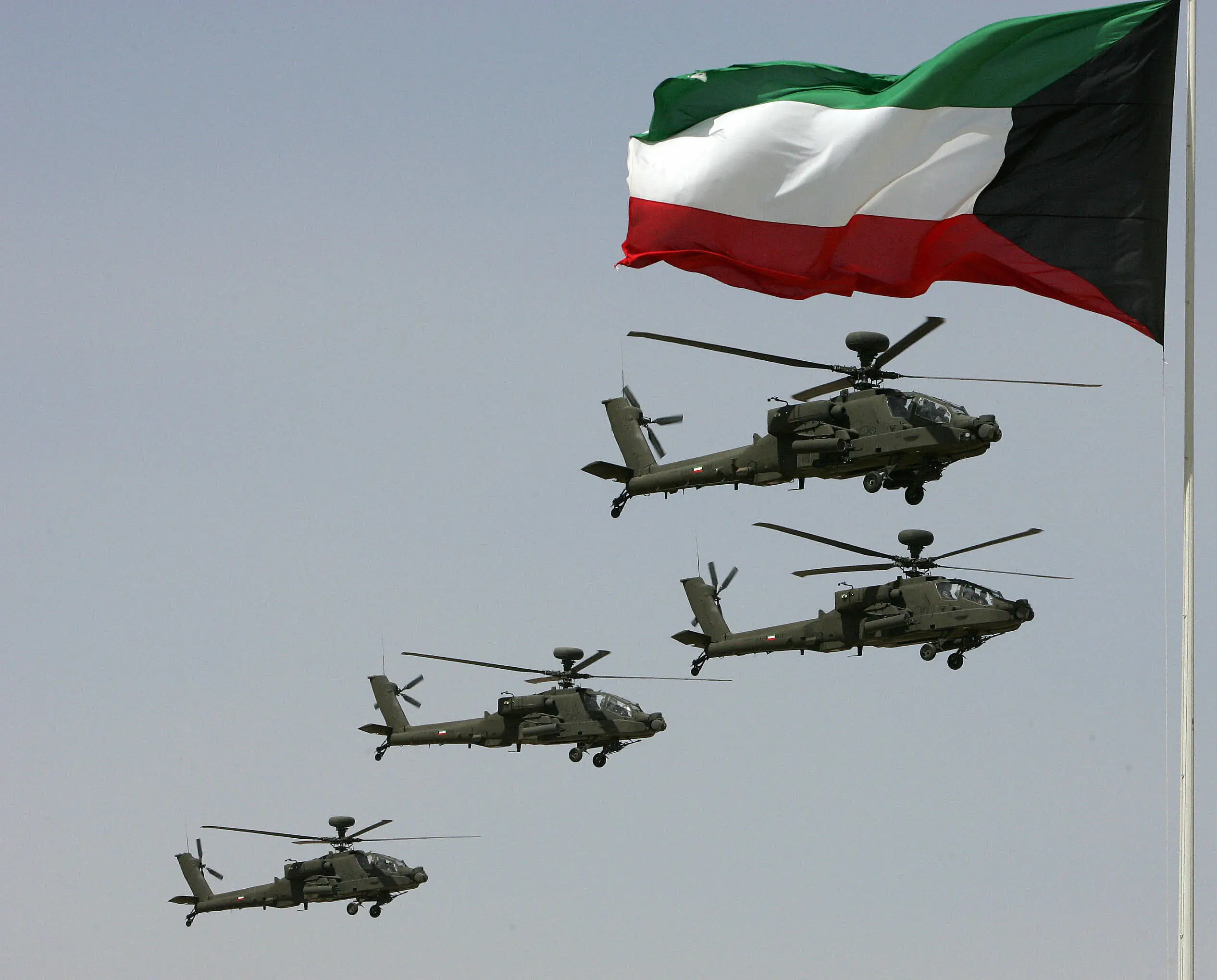 Kuwaiti army helicopters fly past a national flag during a military parade in Kuwait City on March 11, 2009. The show was held to mark the Emir of Kuwait Sheikh Sabah al-Ahmad al-Sabah's accension to the throne three years ago.
