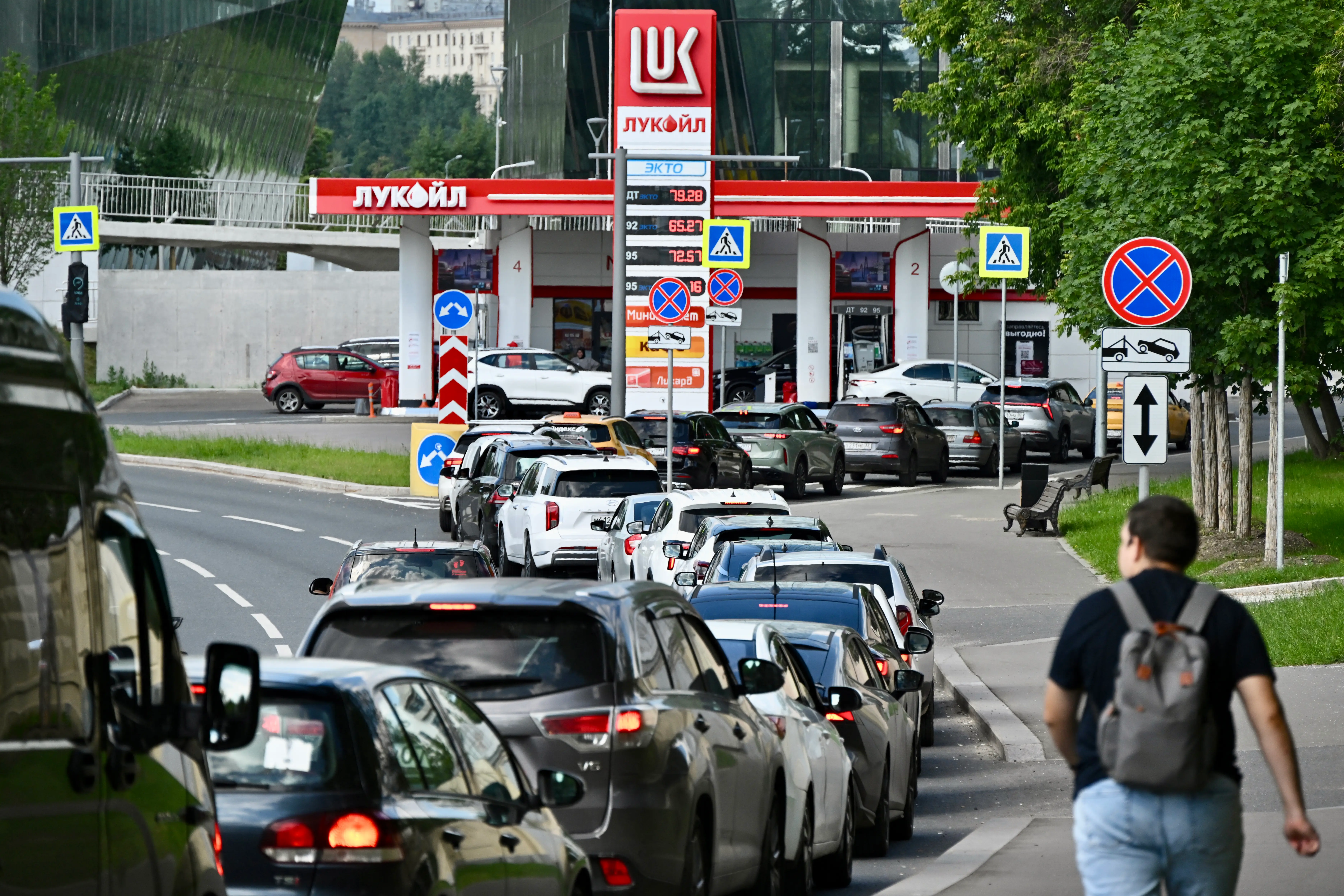 A long queue of cars waits outside a petrol station.