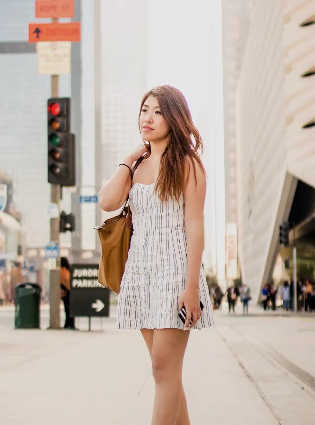 Erika Lee is walking down the street wearing a shoulder bag.