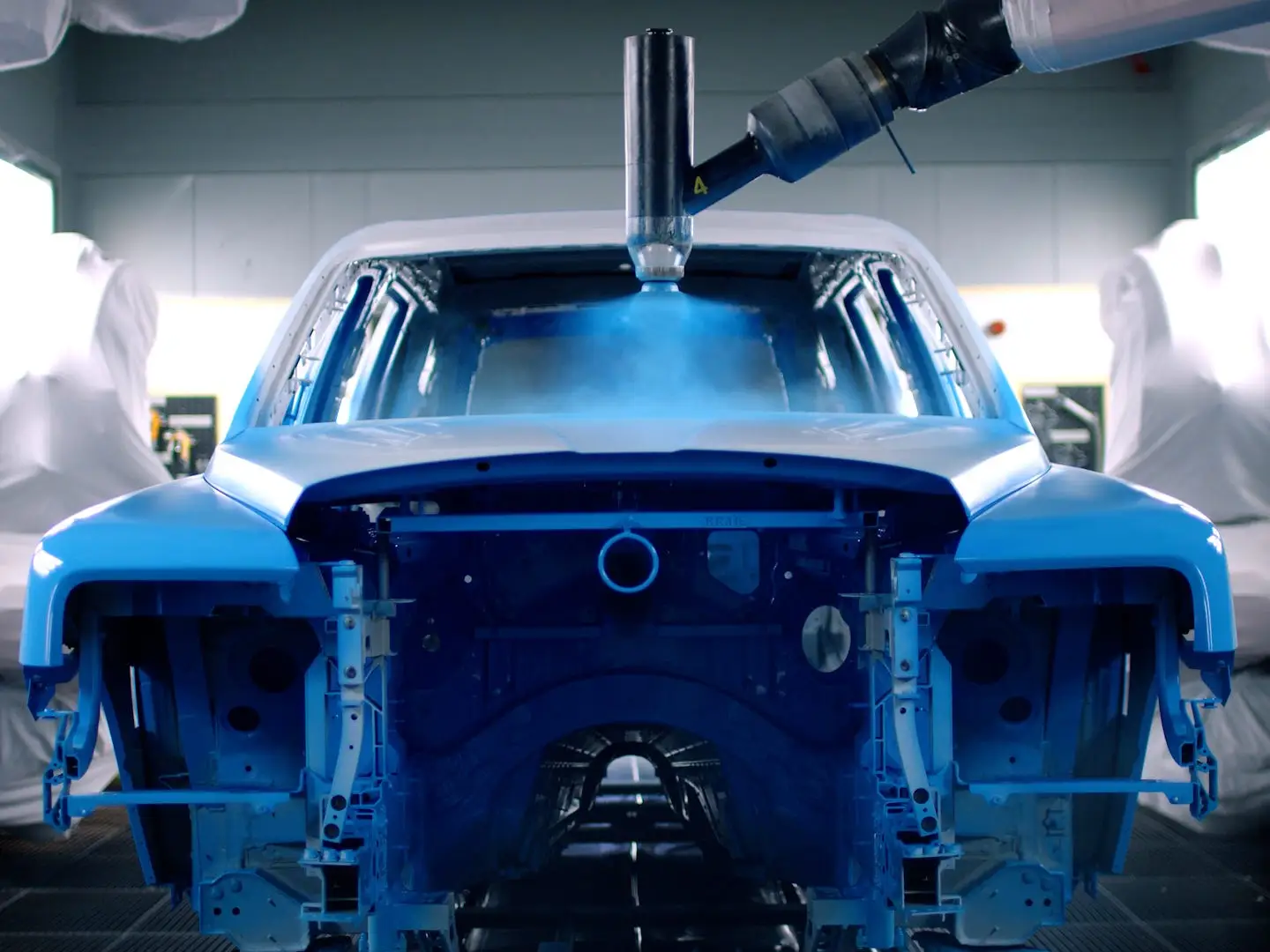 A machine spray painting a car blue