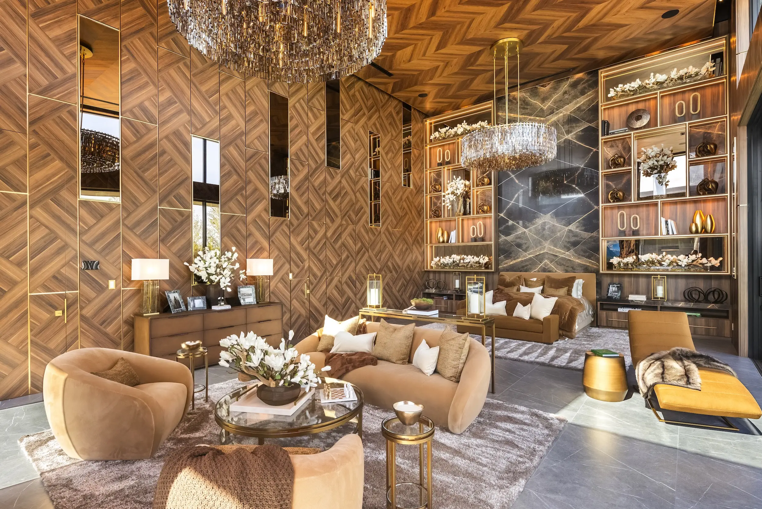 Luxurious wood-paneled bedroom suite with chandeliers, sofas, decorative shelving, flowers, and gold-accented furnishings.