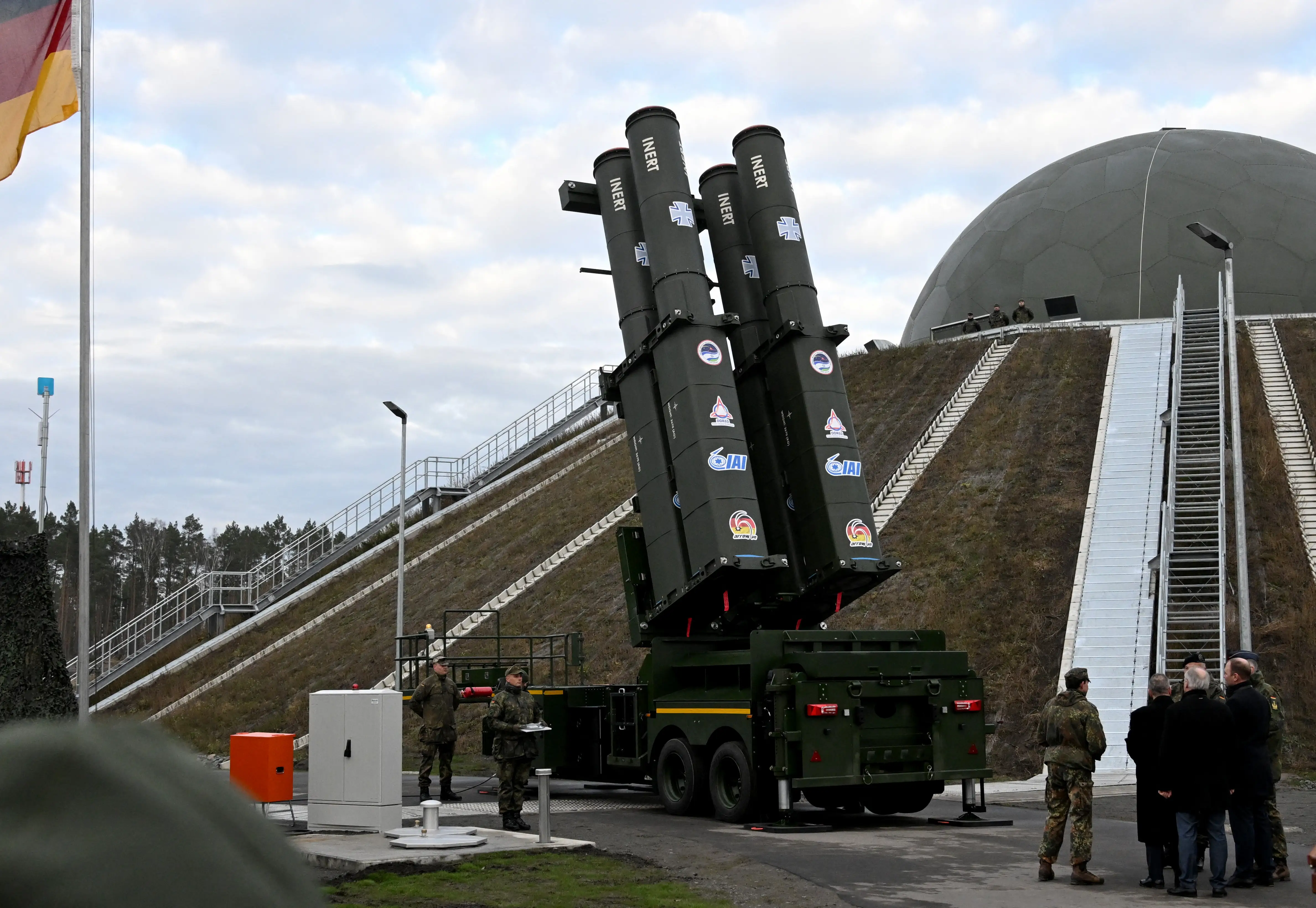 People stand in front of the Arrow 3 shield system during an event of the German Air Force to declare the Initial Operating Capability for the Arrow Weapon System for Germany at the Annaburger Heide Air Base in Schoenewalde / Holzdorf, eastern Germany, on December 3, 2025.