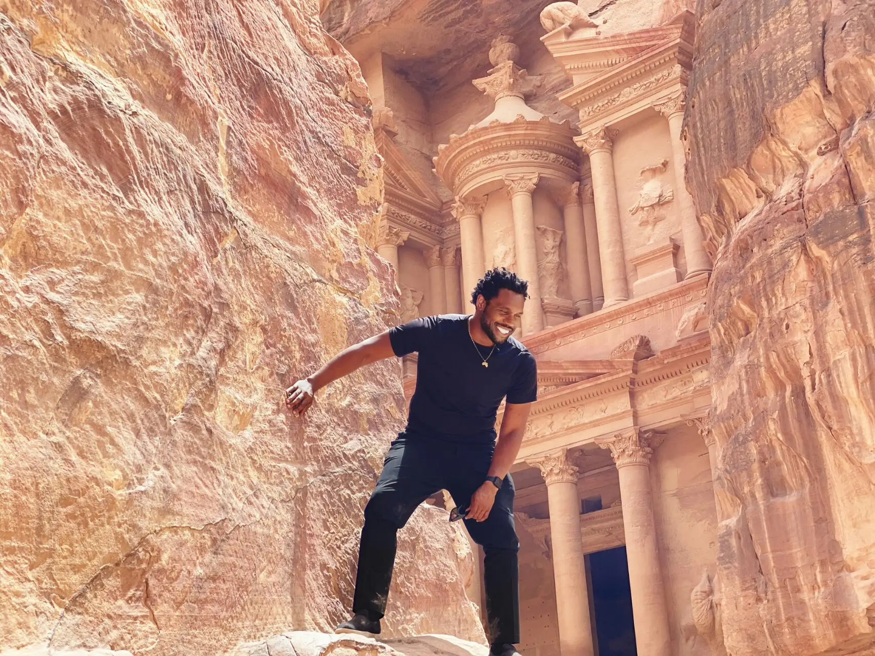 A visitor poses between sandstone canyon walls in Jordan.