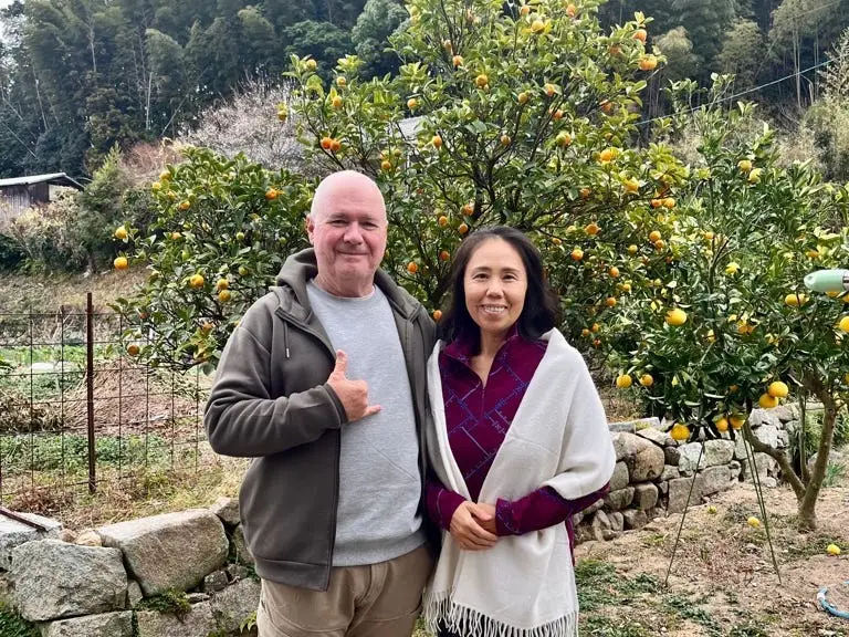 A man and a woman posing with a citrus tree in their garden.