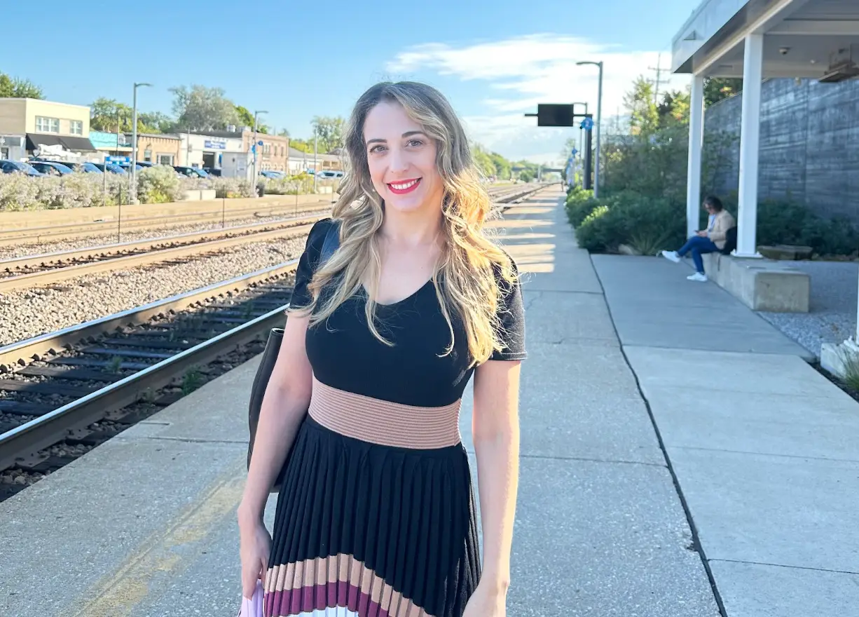 The writer wearing a dress and standing in front of a train station in Illinois.