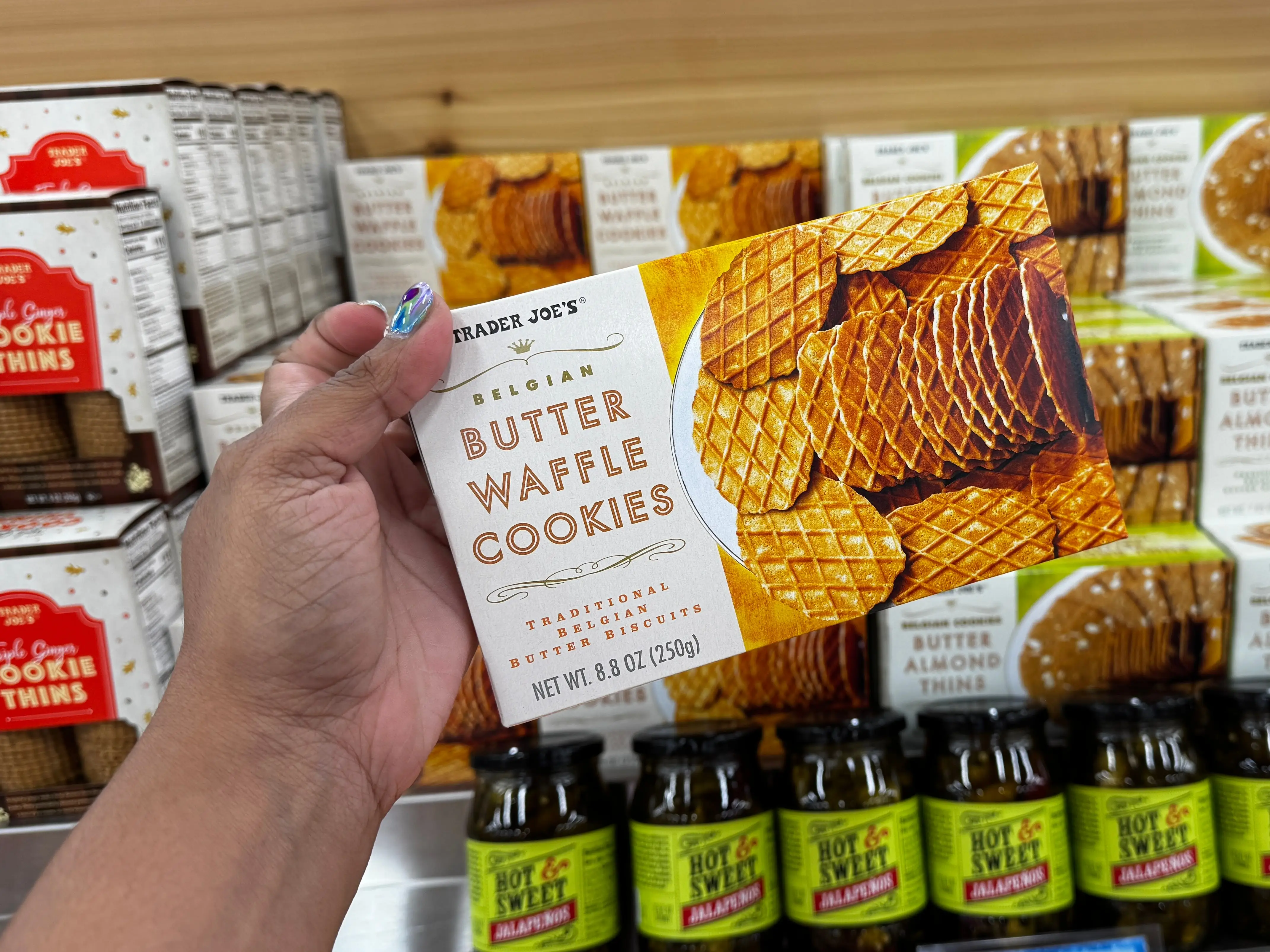 A hand holding a package of Trader Joe's Belgian butter waffle cookies.