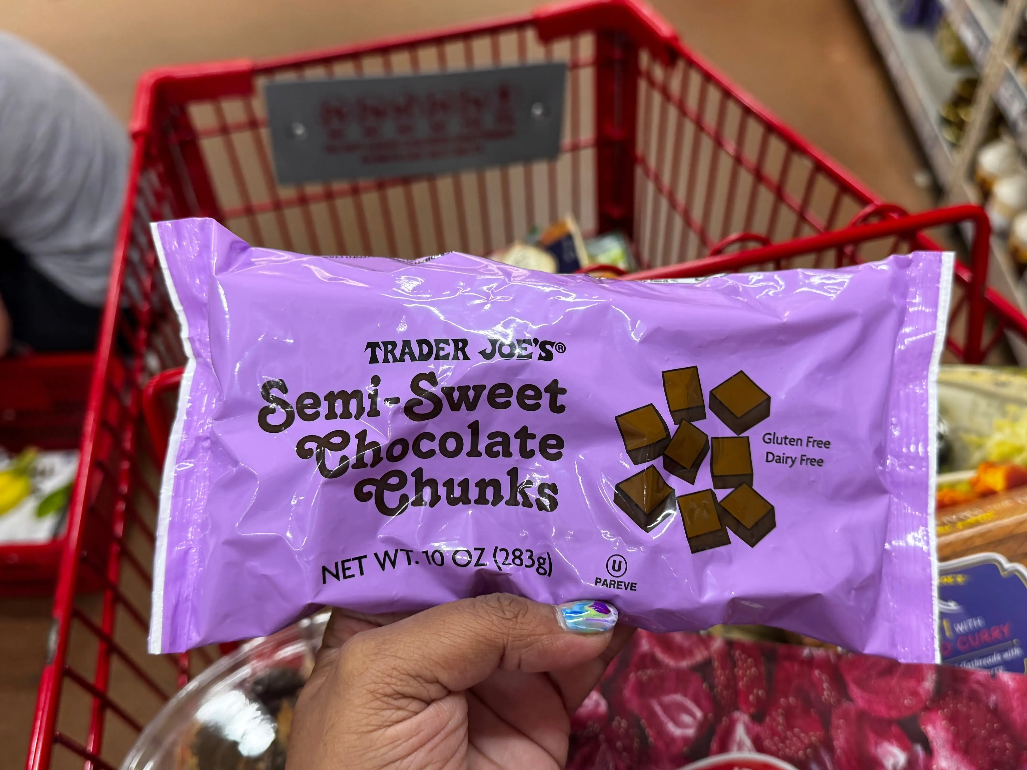 A hand holding a bag of Trader Joe's semi-sweet chocolate chunks.