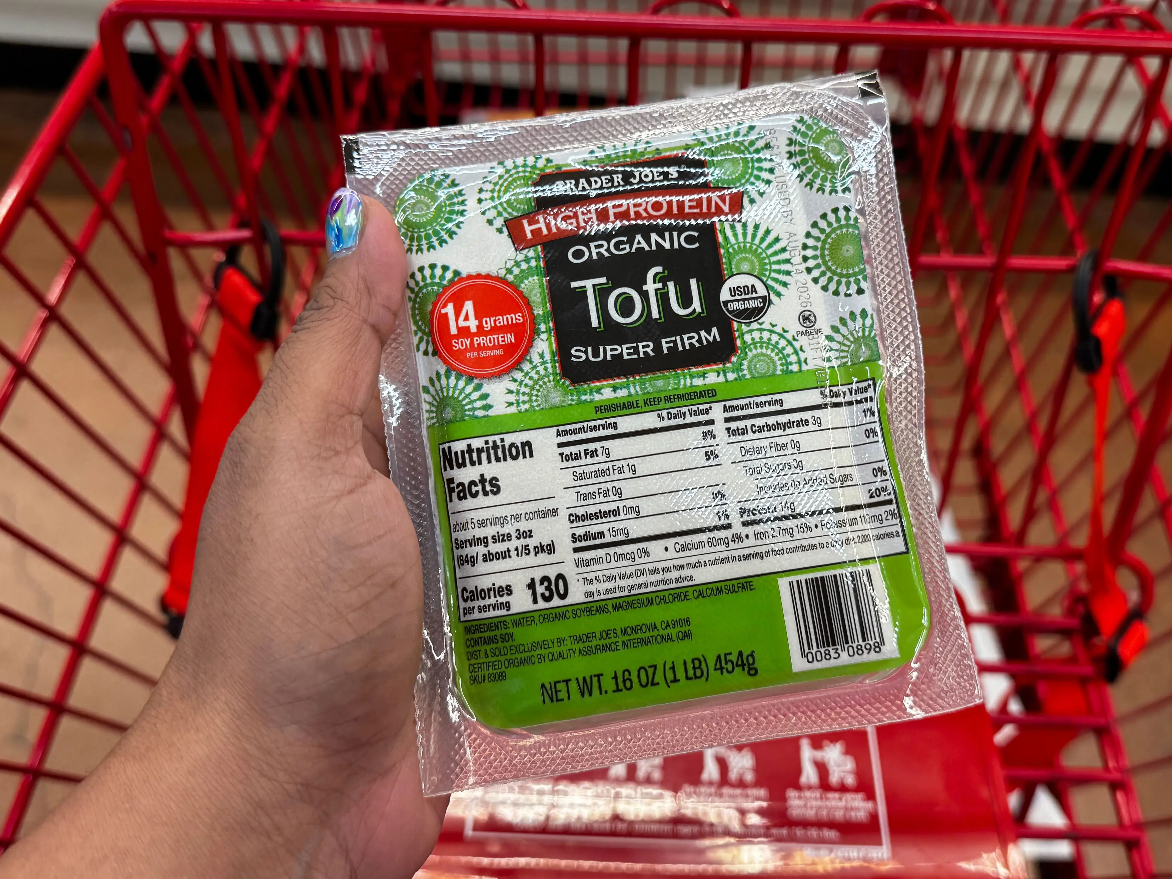 A hand holding a package of Trader Joe's high-protein organic tofu.