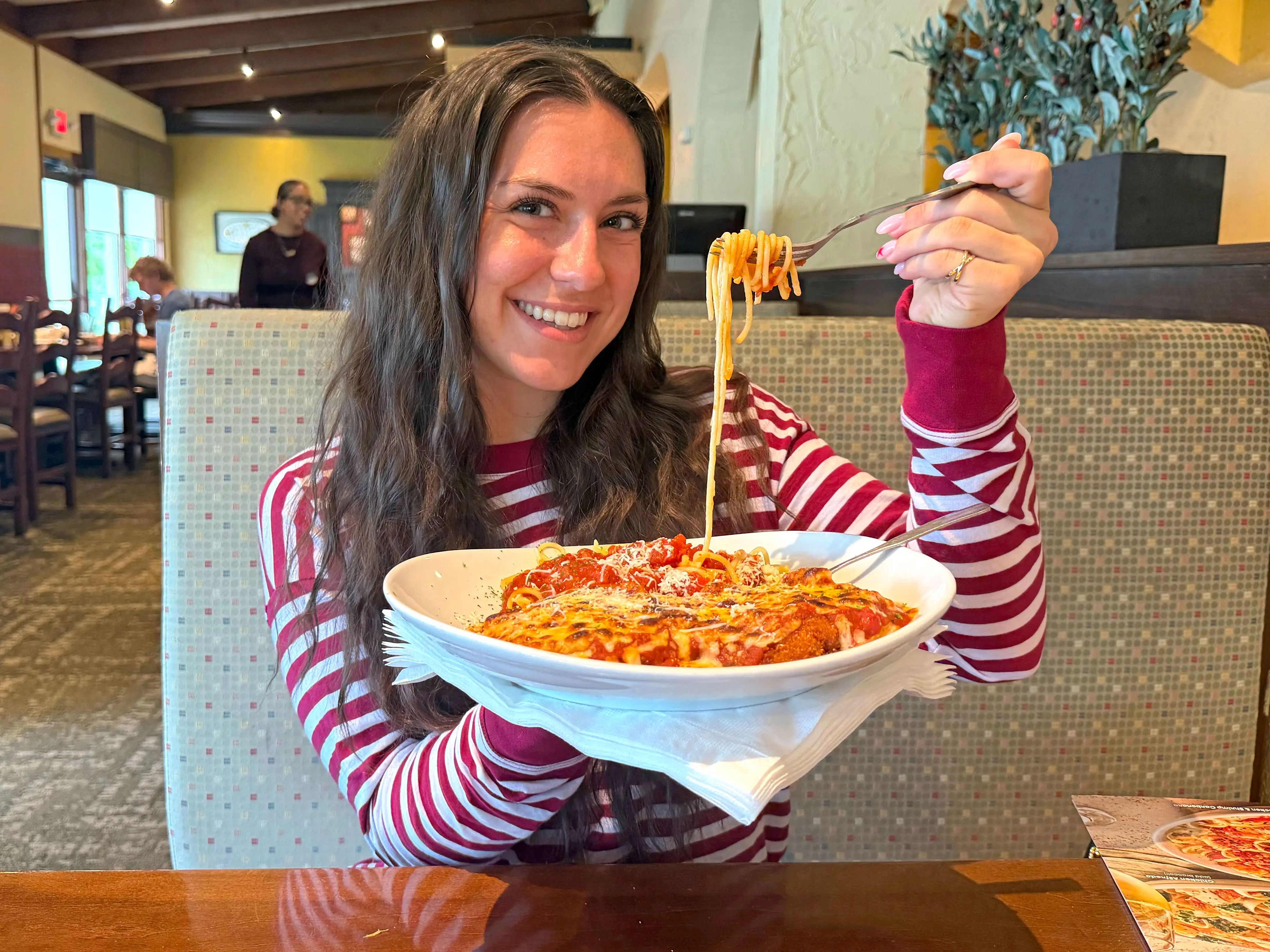 Amanda holds a plate of chicken parm and twirls spaghetti on her fork.