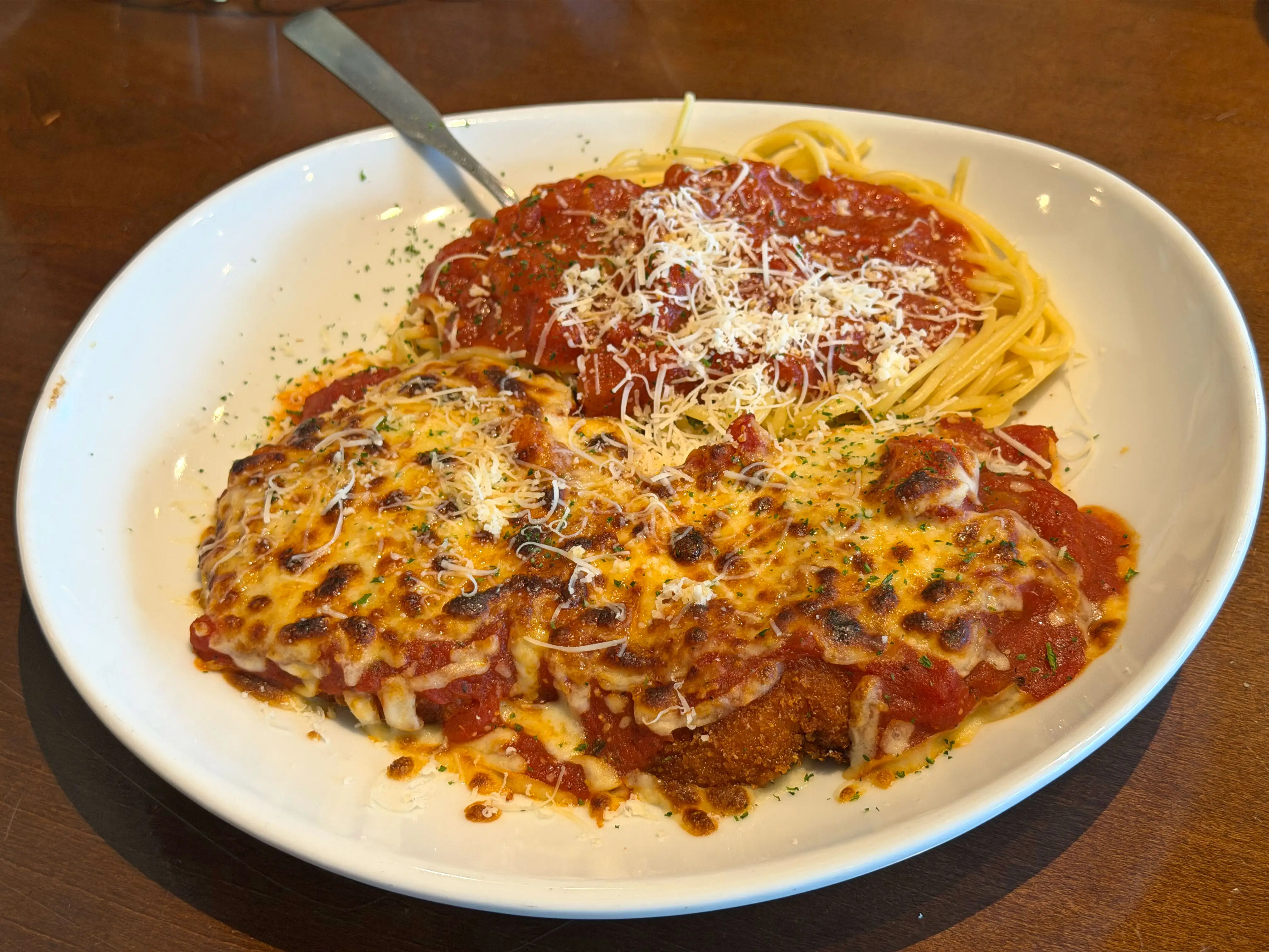 A plate of chicken Parmesan with spaghetti.