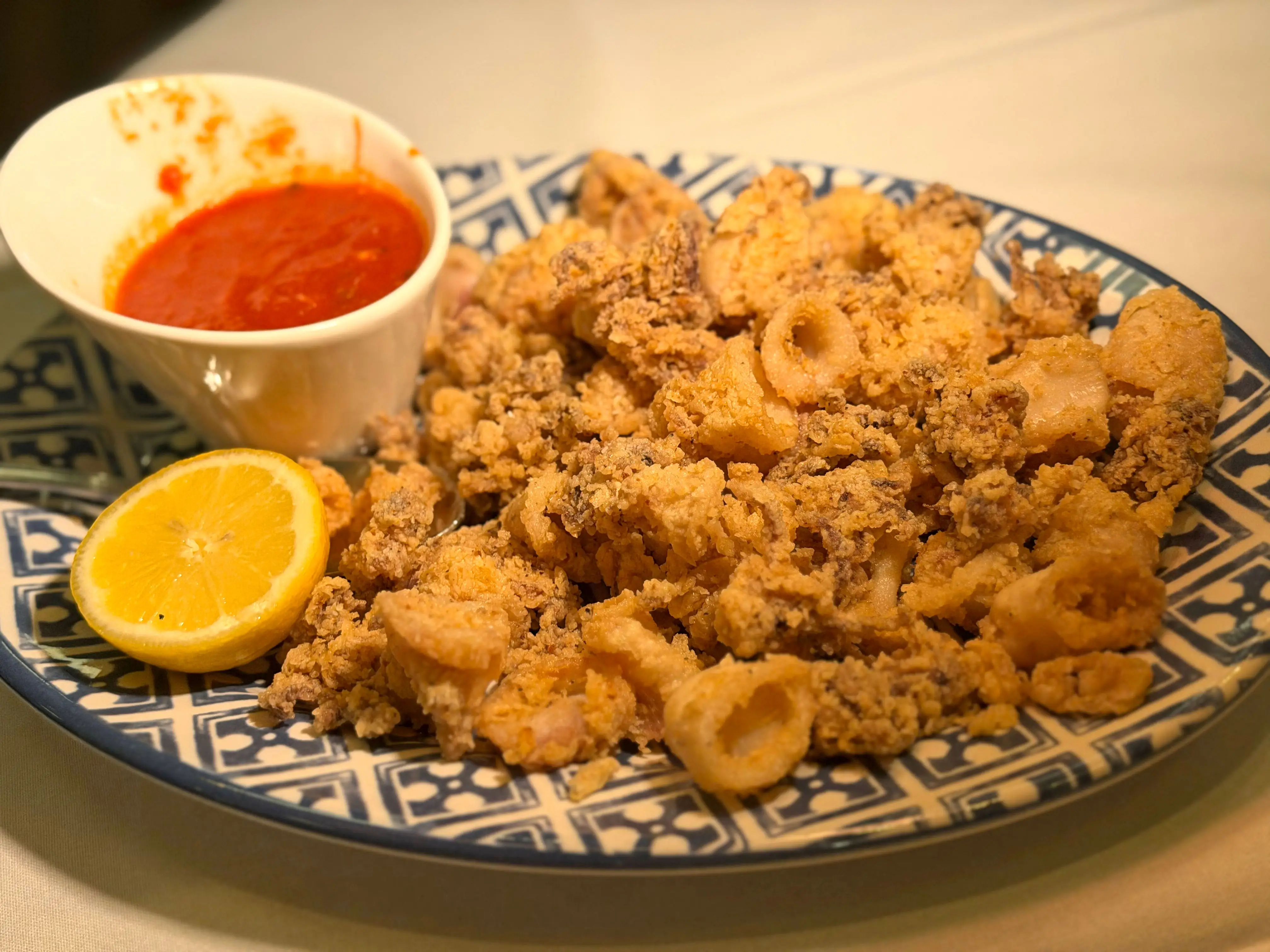 A plate of fried calamari with a side of marinara sauce.
