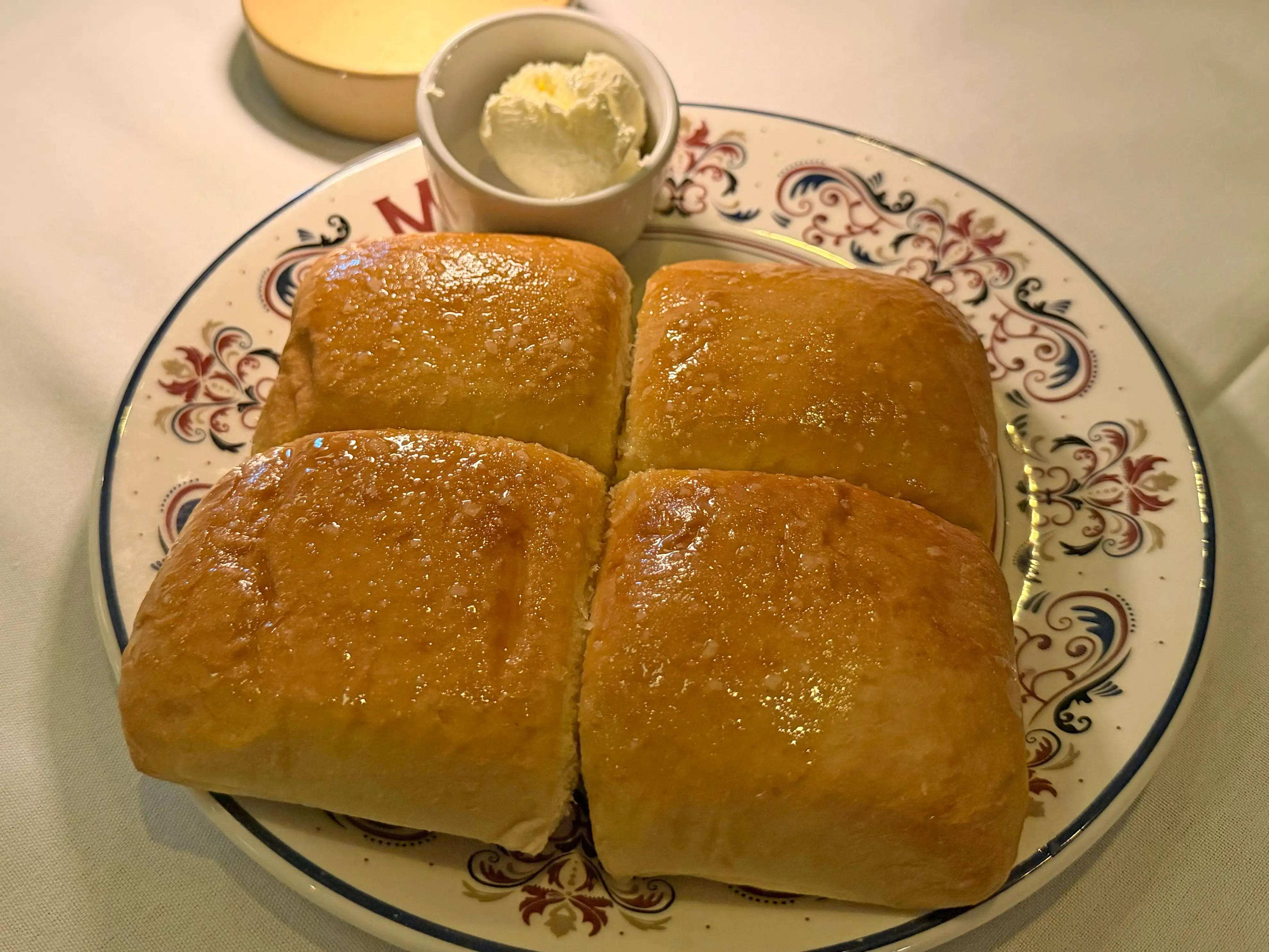 Four rolls on a plate with butter.