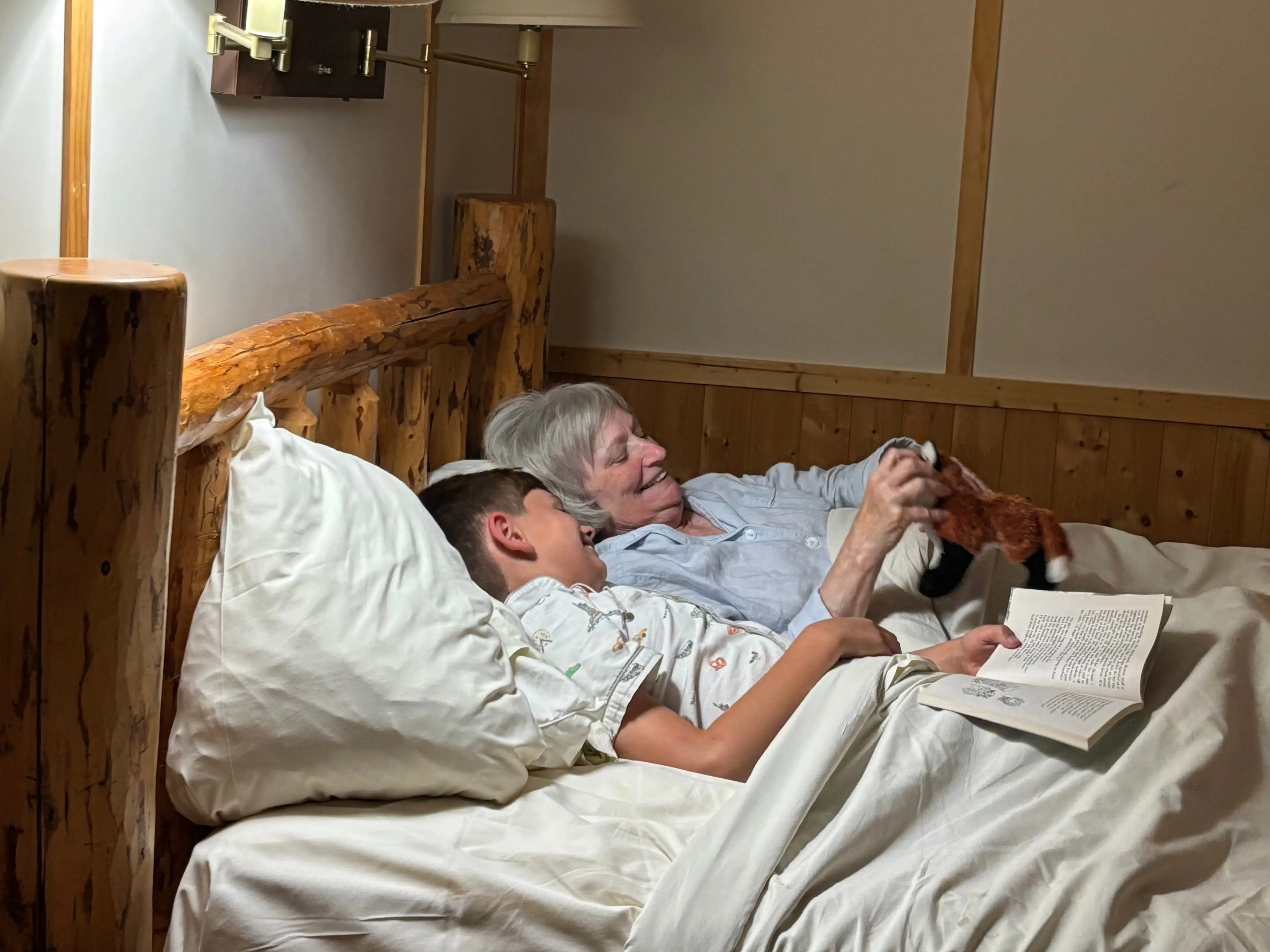 A photo of a grandmother and her grandson laughing in bed together.