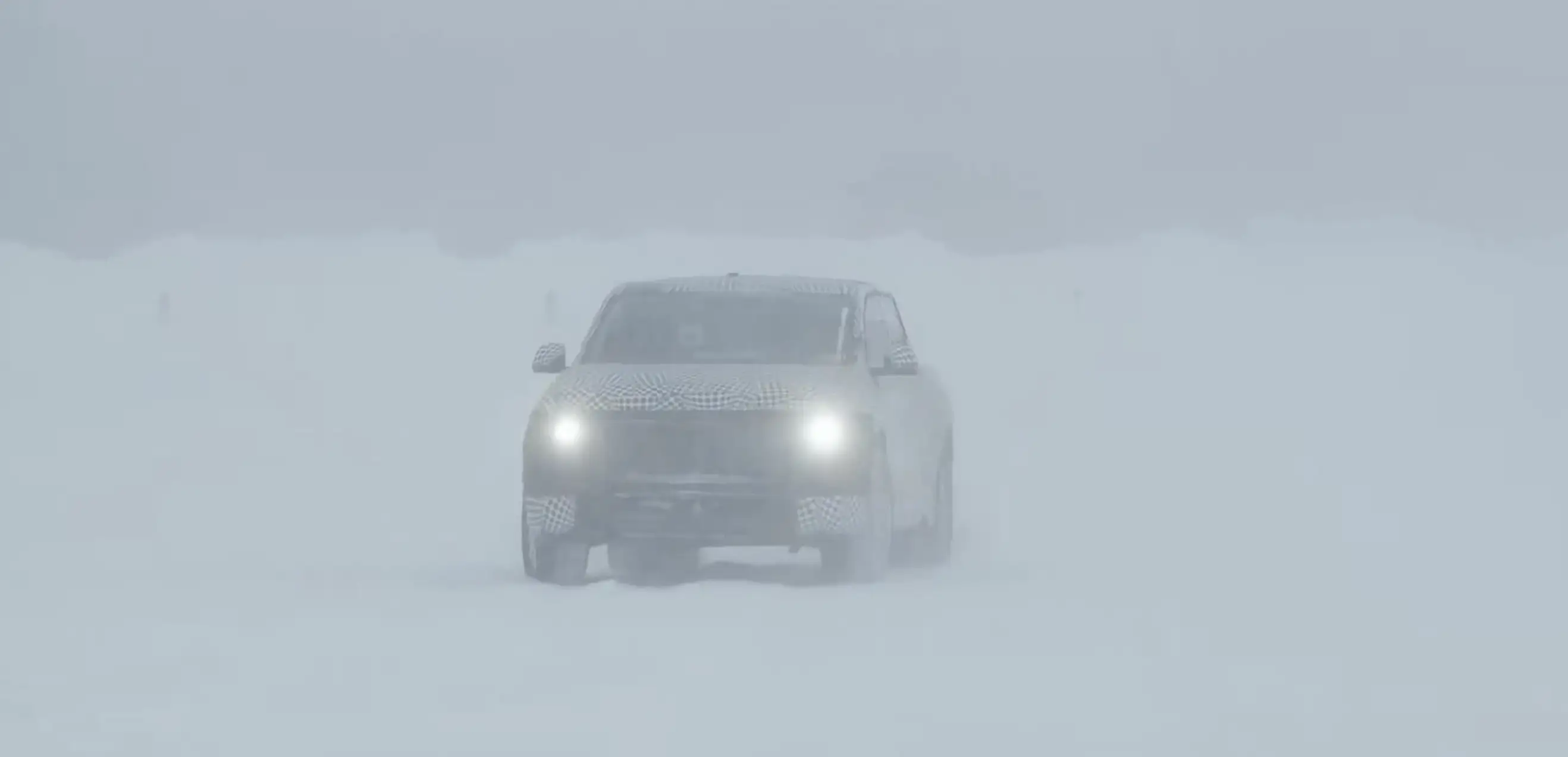 A prototype of the new Ford truck, covered in a dizzying camouflage wrap, drives through a snowy field.