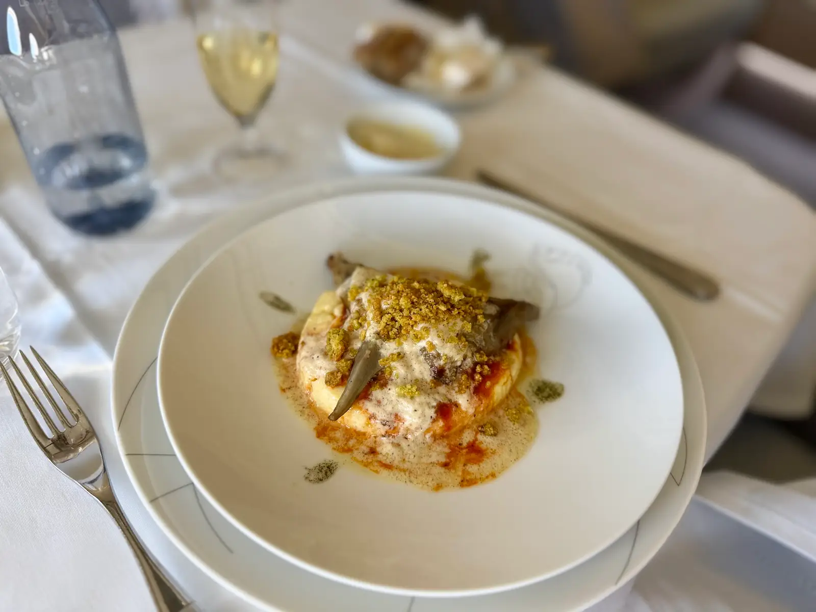 Grilled artichokes, creamy polenta with Comté cheese, smoked vanilla. on white plate on Air France flight