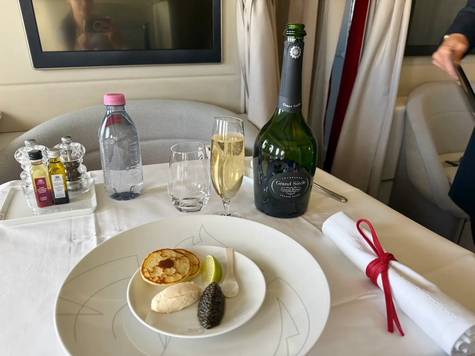 French sturia caviar quenelle, vodka and lime whipped cream, Laurent-Perrier Grand Siècle no 26 champagne on white tablecloth covered table on Air France flight