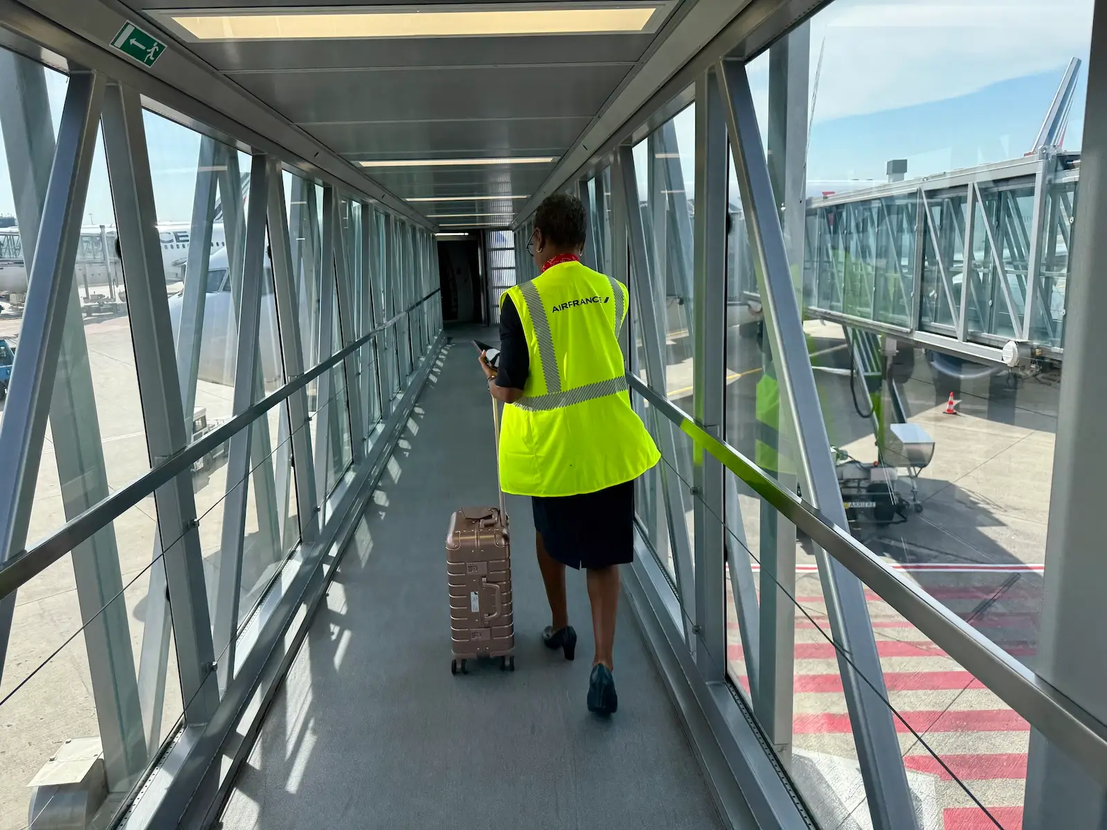 PErson in neon vest wheeling suitcase through airport