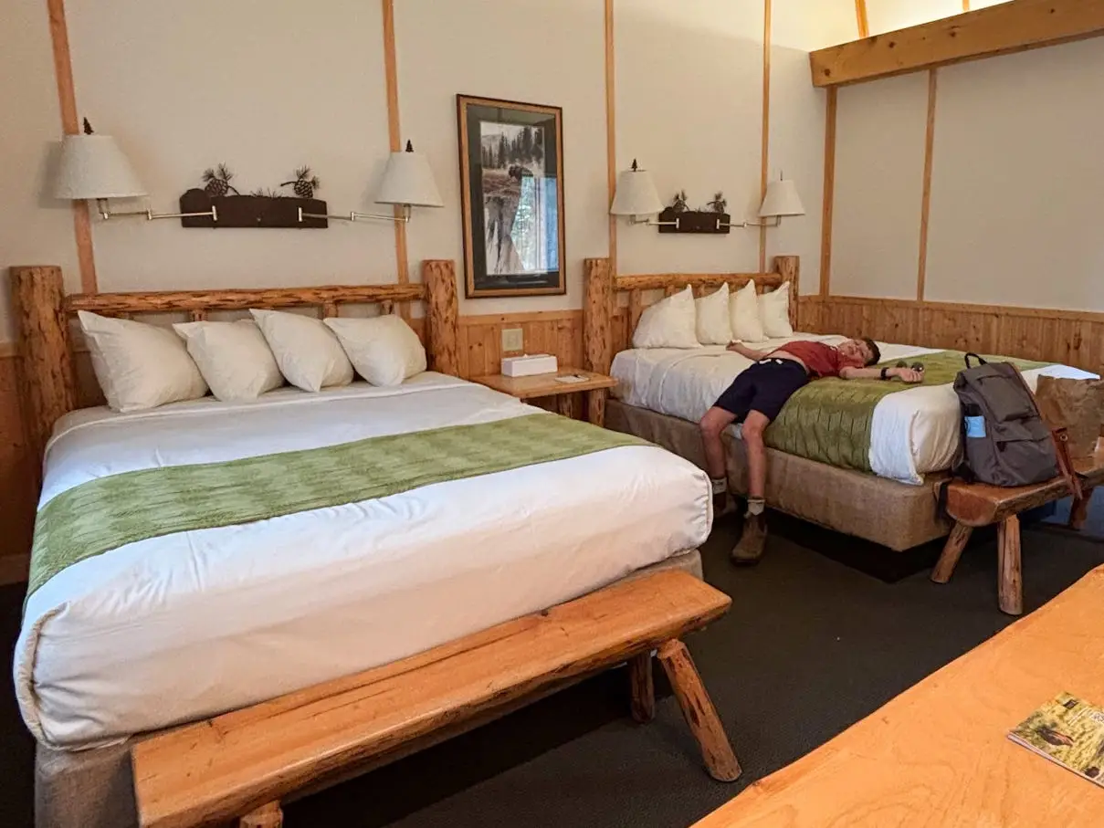 A boy lying across a bed in a hotel room near Yellowstone National Park.