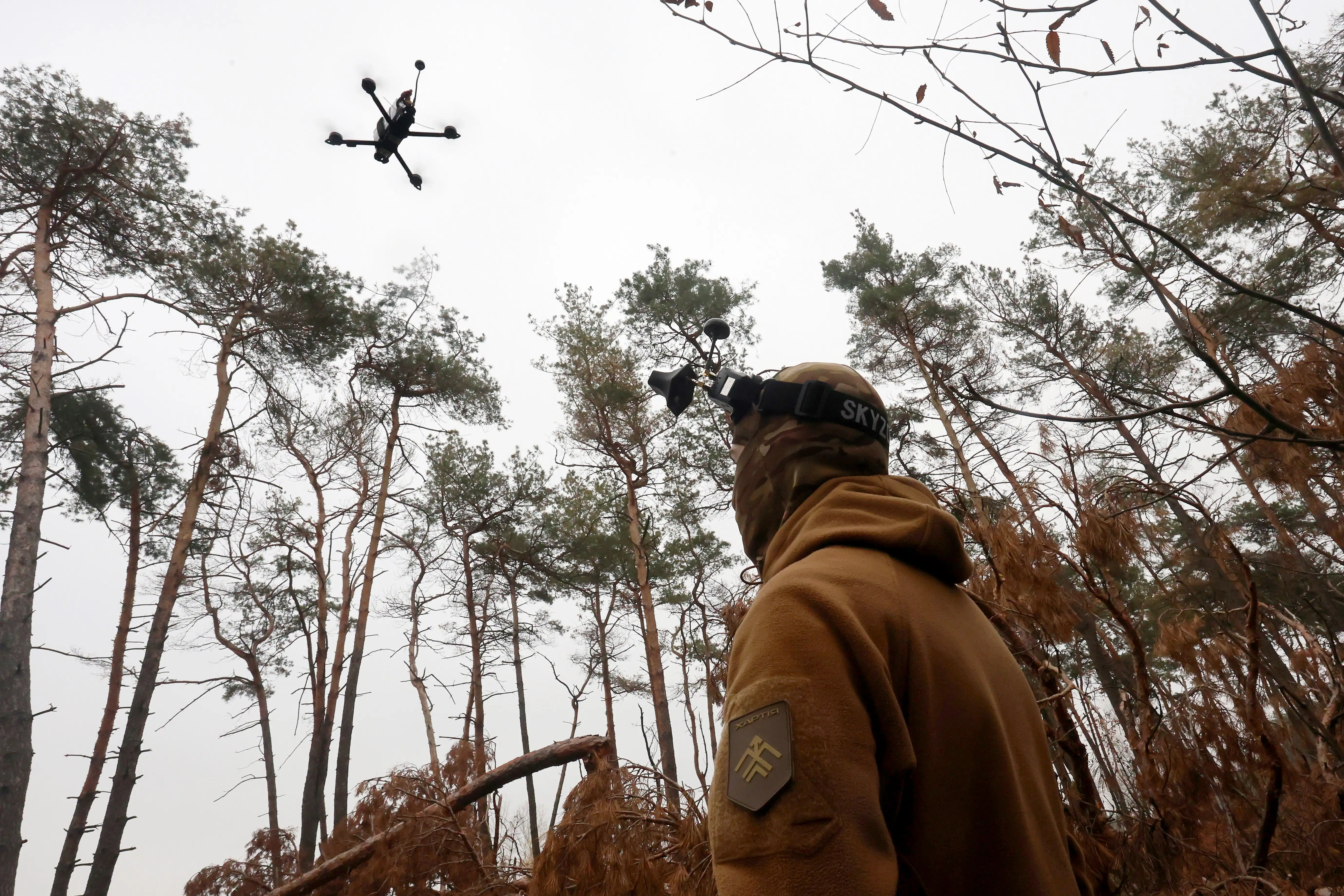 A Ukrainian soldier looks up at an FPV drone.
