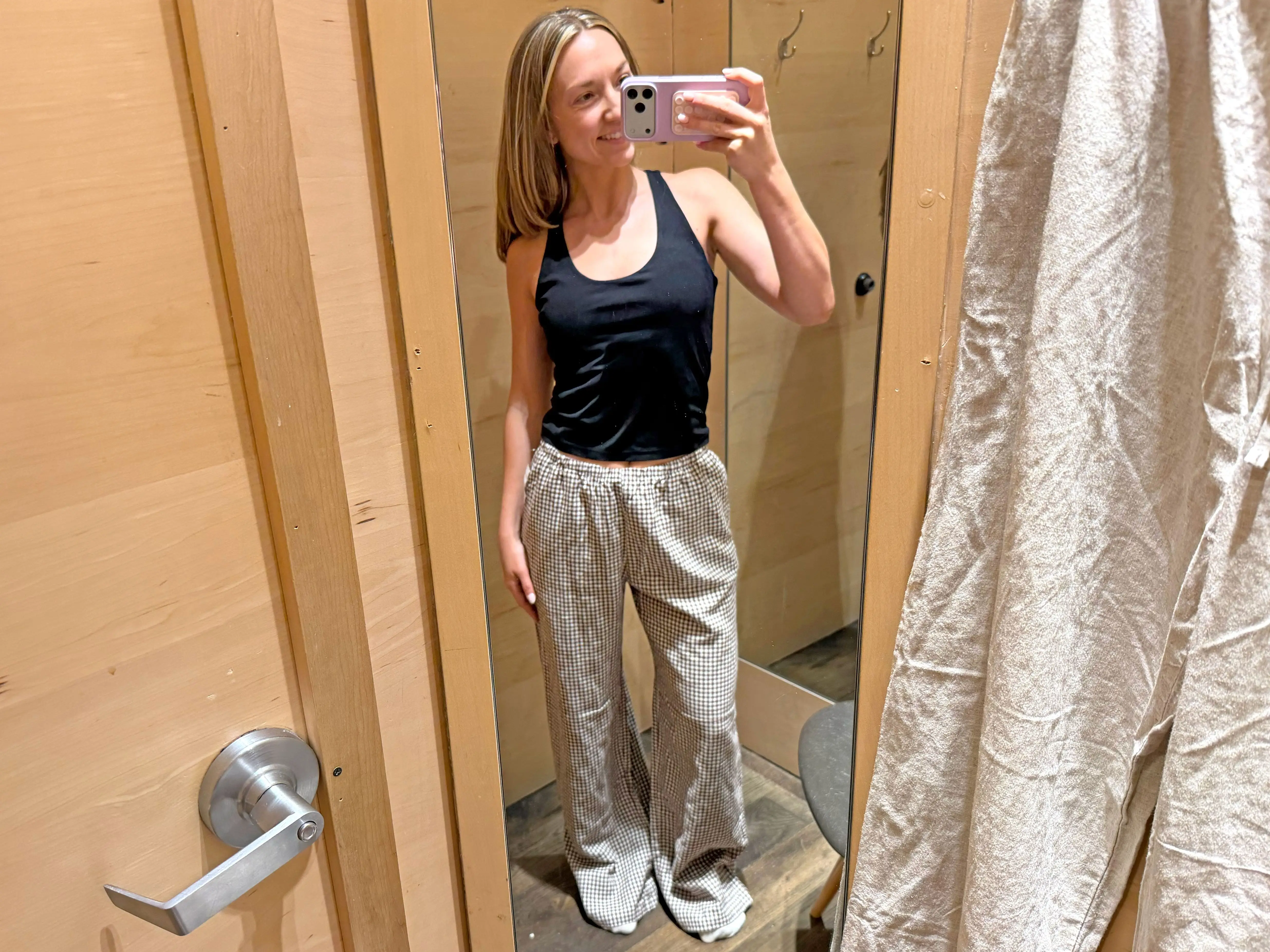 Chloe wears a pair of brown-checkered linen pants in a fitting room.