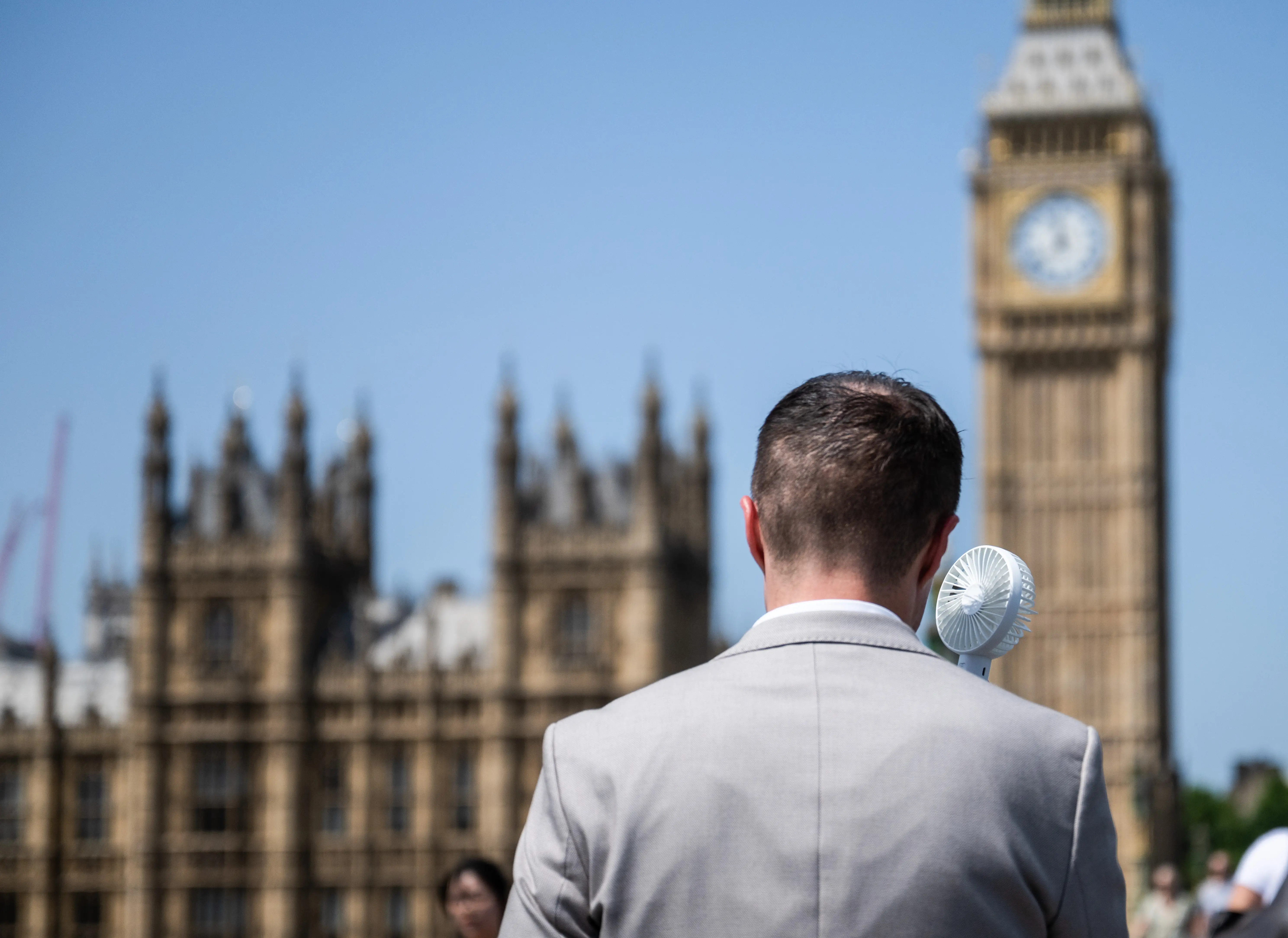 A worker used a portable electric fan on Westminster Bridge during a heat wave in London, UK, in June 2026