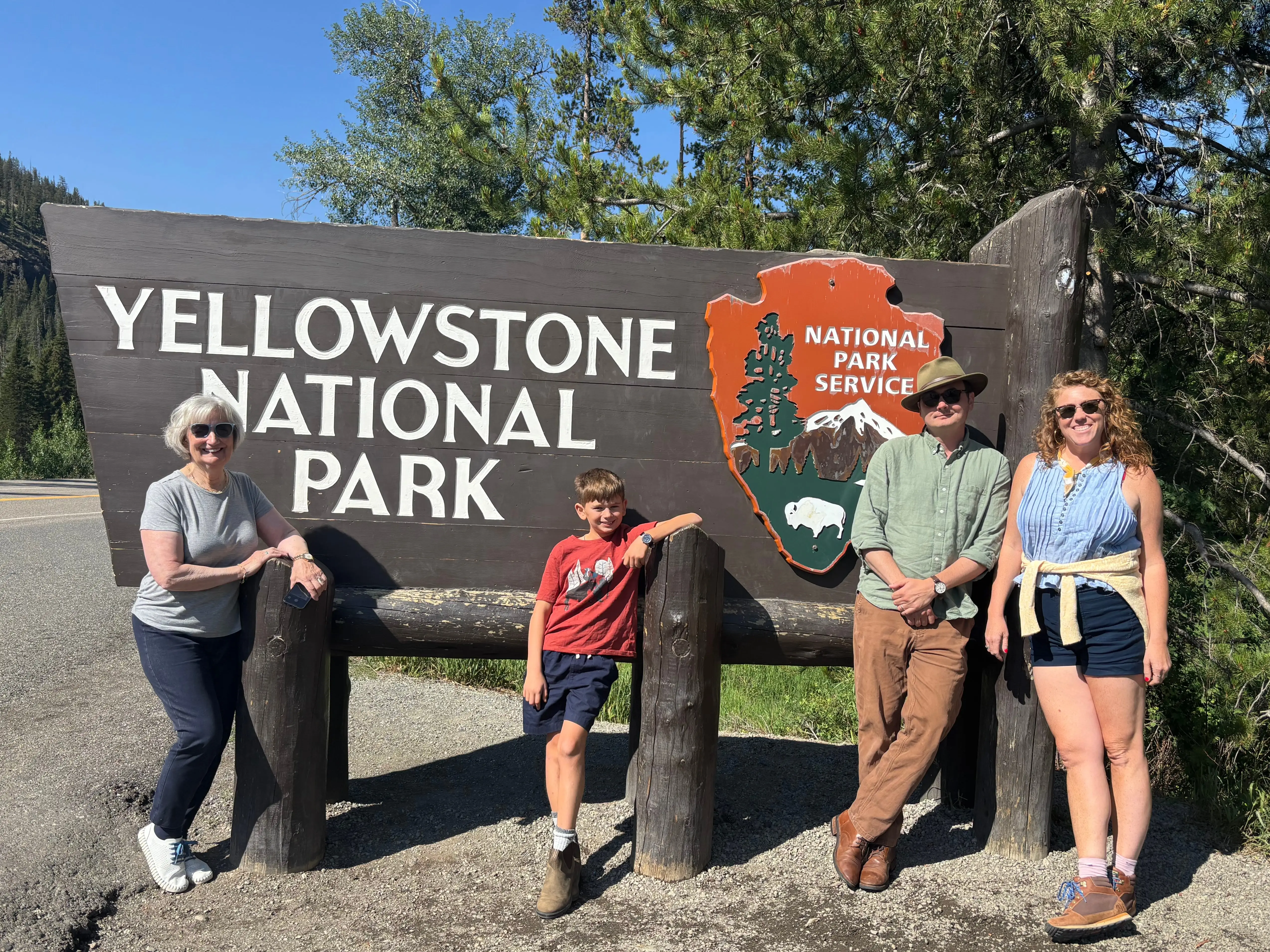 A family poses in front of the sign for Yellowstone National Park in Wyoming.