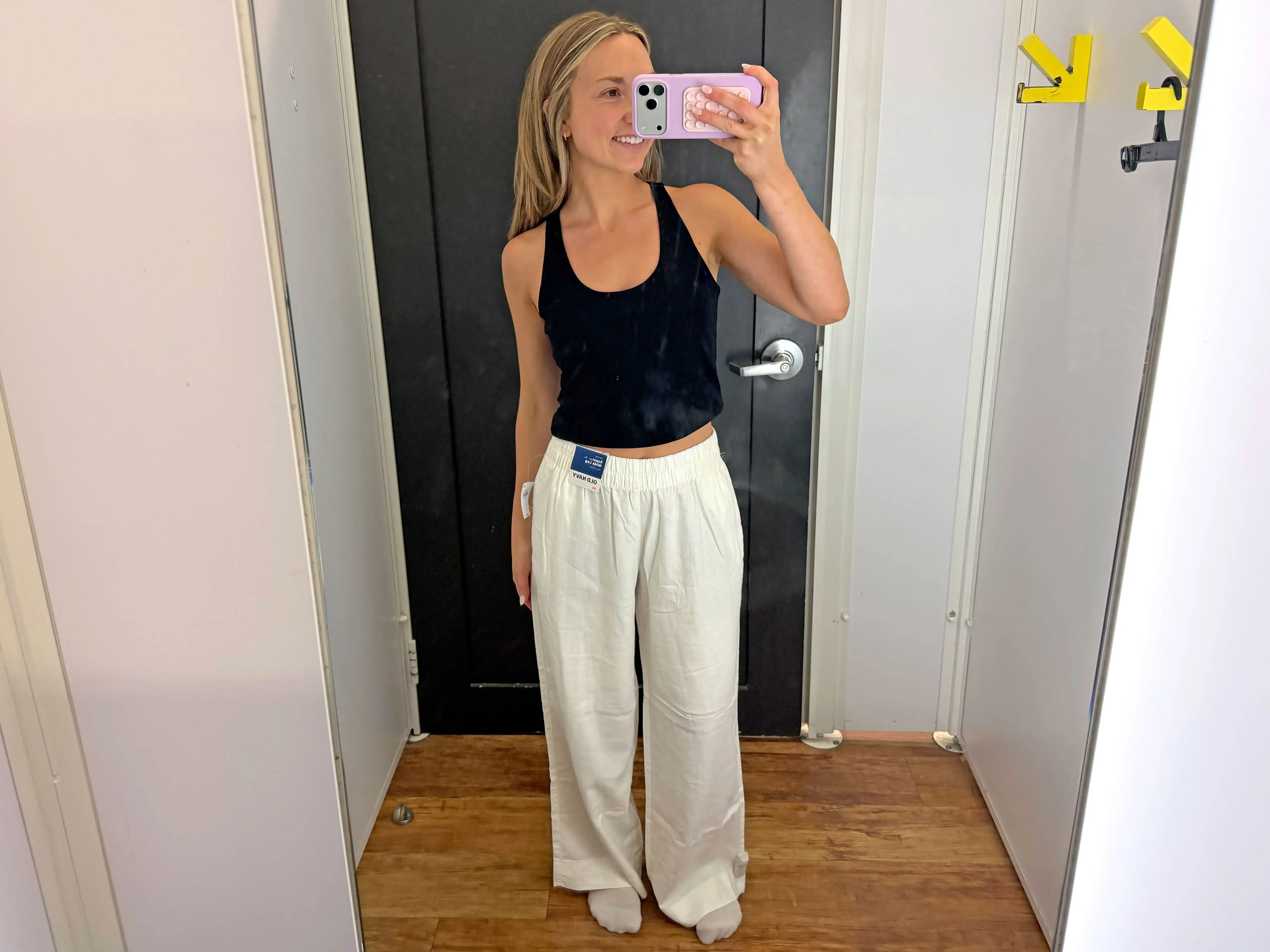Chloe wears a pair of white linen pants in a fitting room.