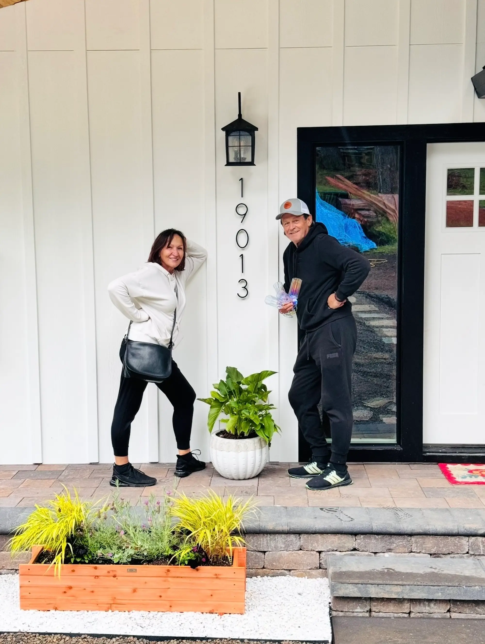 A couple stands outside their home.